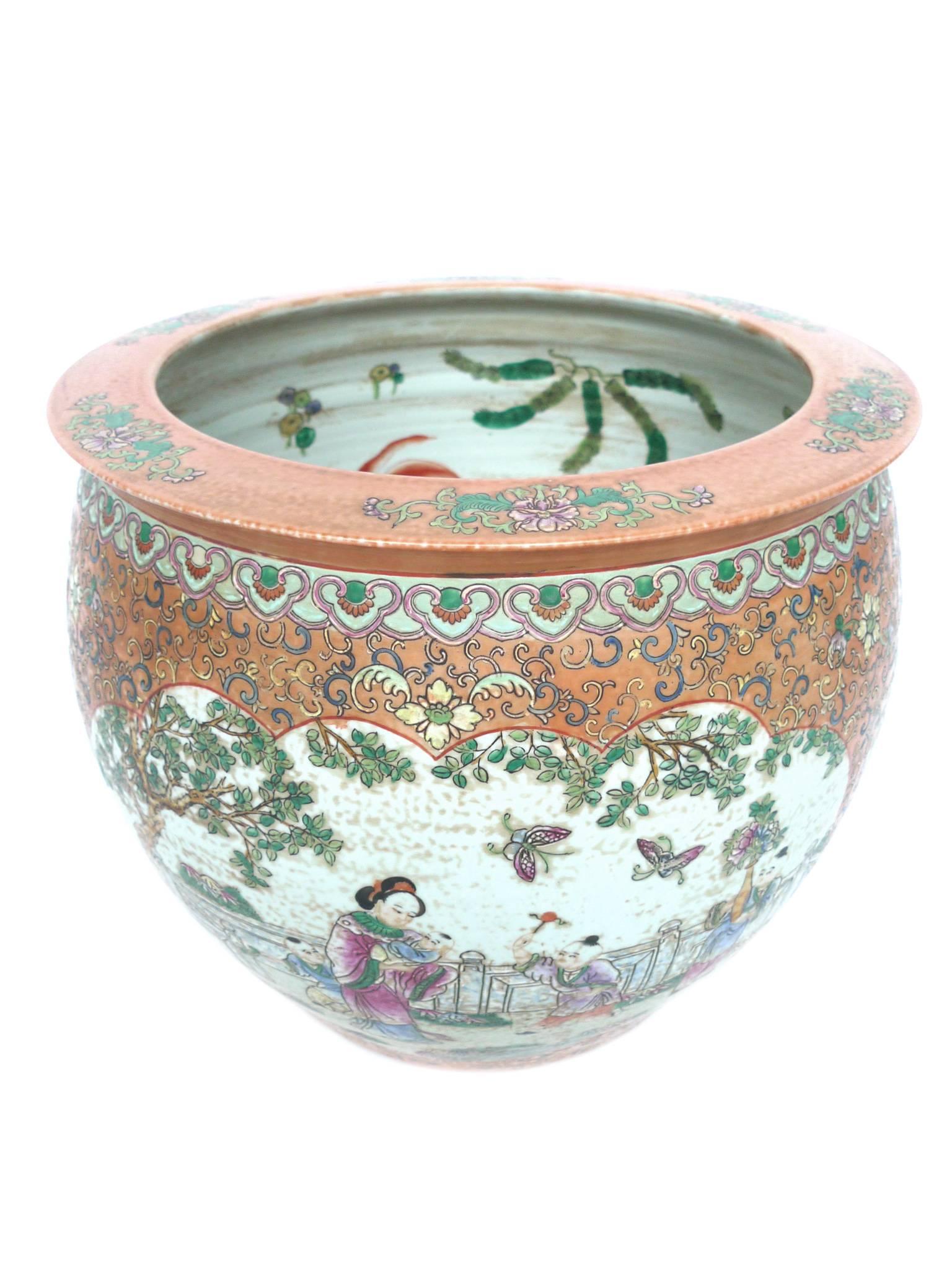 This peach-colored ceramic fishbowl is beautifully hand-painted. The exterior design depicts pastoral vignettes of figures in a garden, surrounded by a floral pattern, while the interior's design is of goldfish and plant flora. This design is