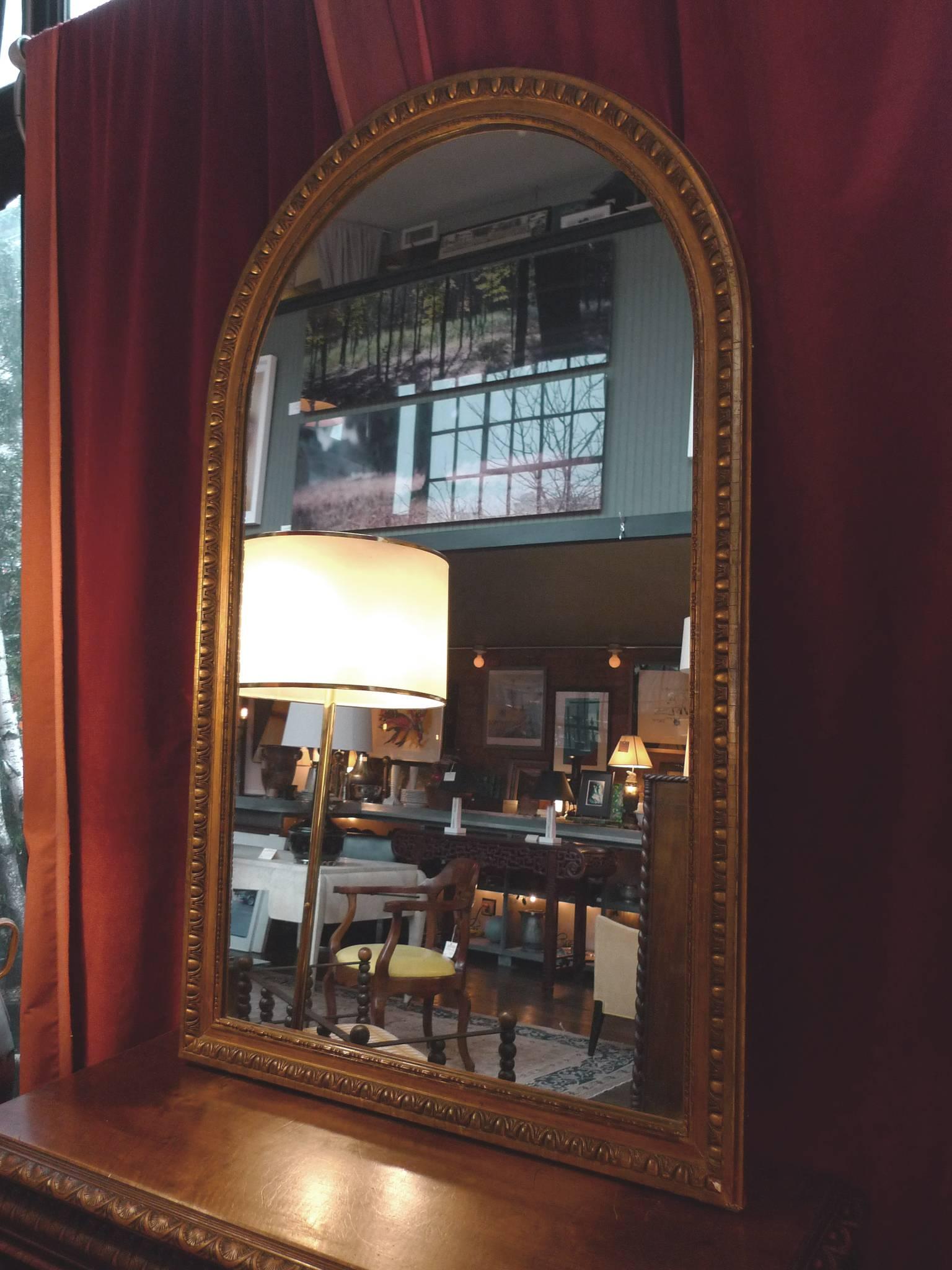 This 19th century French overmantle mirror has a gilt frame cut in a lovely waterleaf molding. It stands at approximately 5 ft. 3.5 in. and measures 40 in. wide. The frame is 1.5 in. thick. 