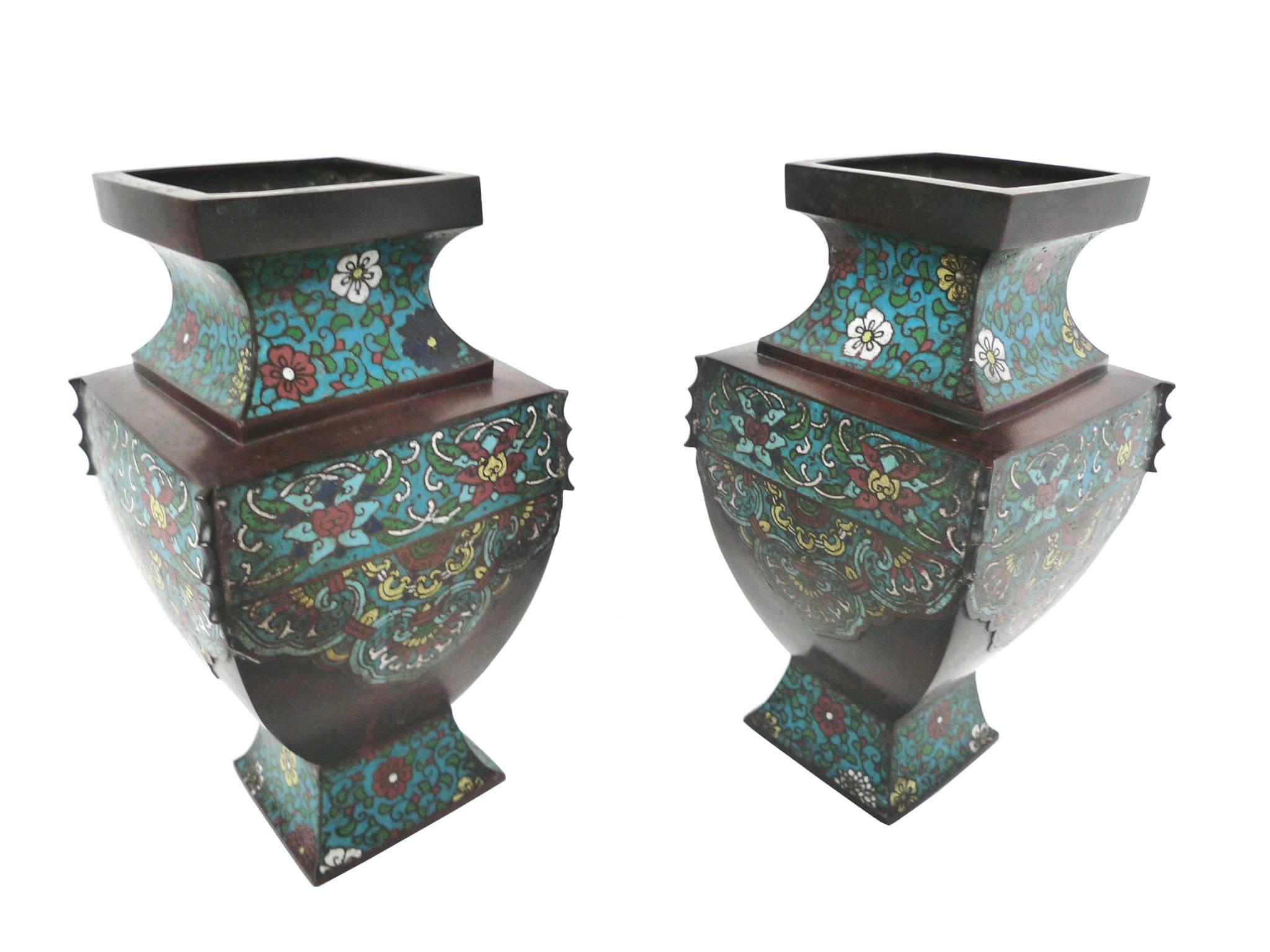 These early 20th century Asian bronze urns have beautiful designs rendered in the cloisonné technique. The floral patterns adorn the bronze in a colorful, rich palette.