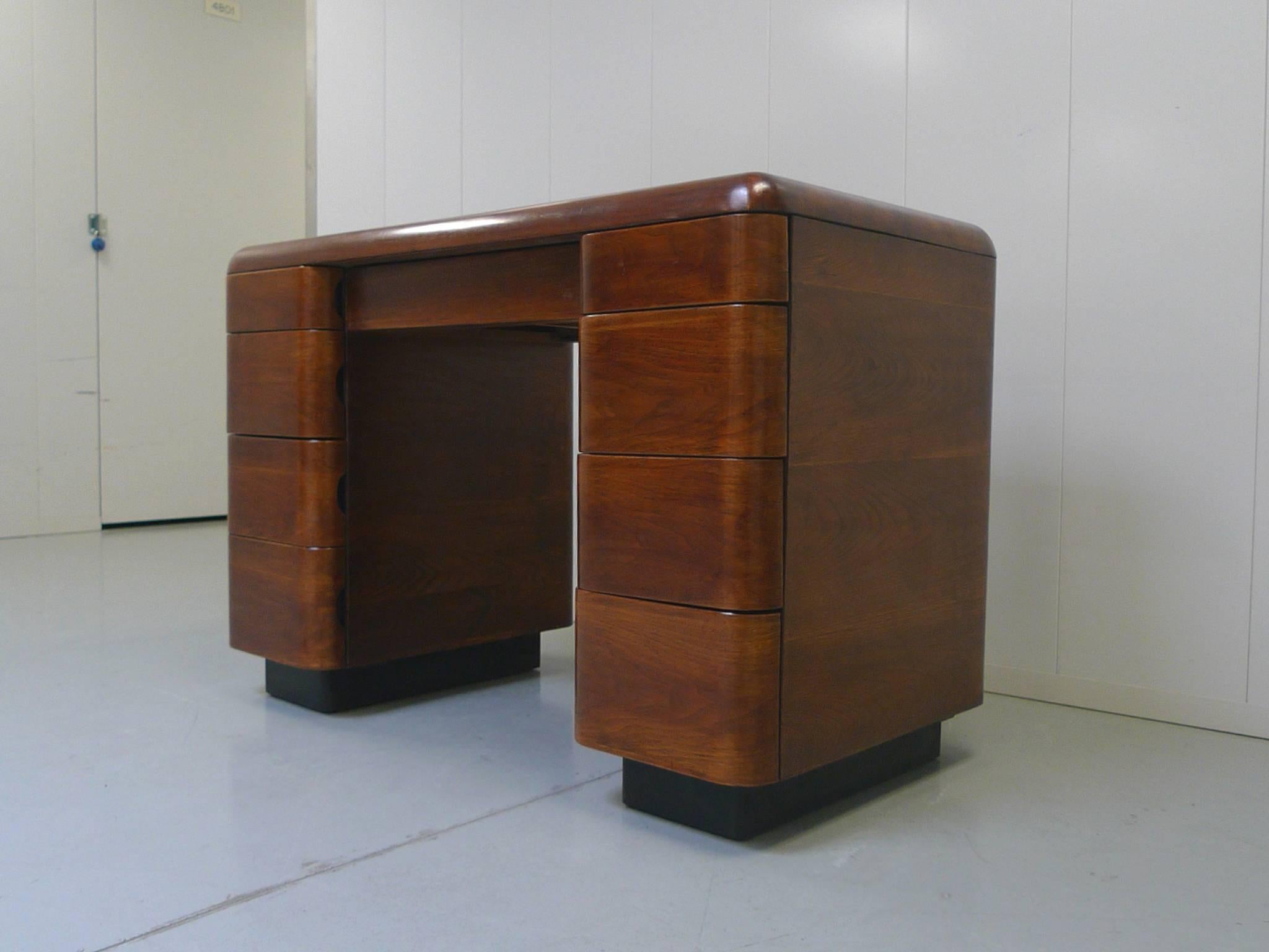 This Art Deco-style desk was designed by Paul Goldman in 1946 for Plymodern Furniture. Goldman was renowned for his use of bent plywood. The process of Plymold allowed for the beautiful curves of this Tanker-like desk to be formed. The bentwood is