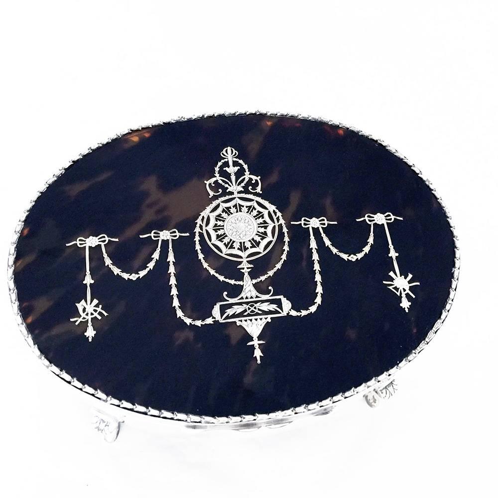 A large oval sterling silver jewelry box standing on four cast legs. The oval tortoiseshell lid is inlaid with silver in the style of the Art Nouveau period. 

In fine condition the interior of the box is lined with trimmed blue silk. 

By one