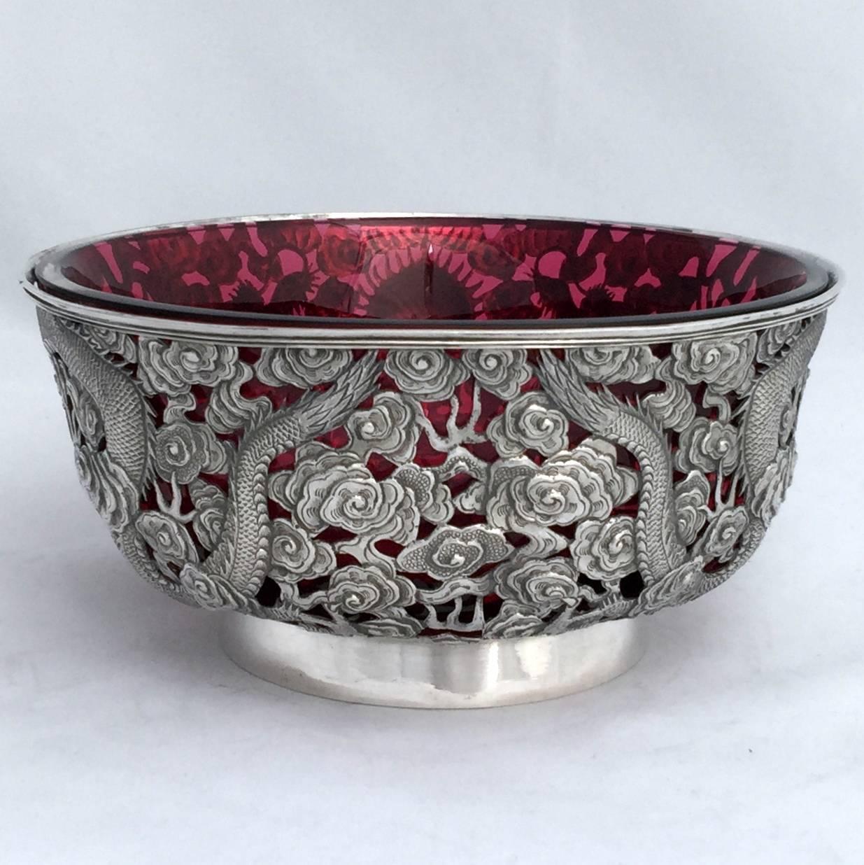 A finely worked Chinese export silver (CES) flared presentation bowl. The pierced and repousse worked body has two four clawed dragons cavorting in the clouds. They chase the magic pearl which forms a reserve for engraving. The repoussed work is