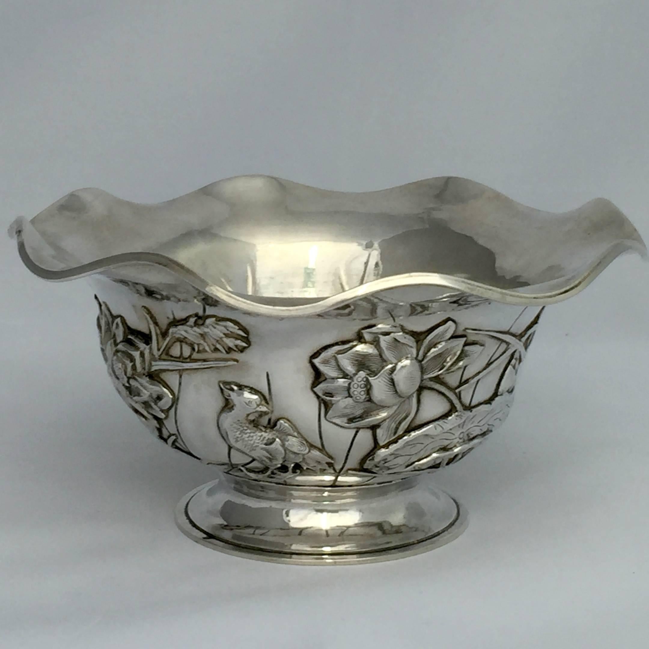 A double skinned Chinese export (CES) silver bowl using the lotus motif. The whole bowl is in the form of a lotus. The flared body of the bowl is decorated with birds nestling amongst lotus flowers, buds and leaves. Even the base is in the form of a