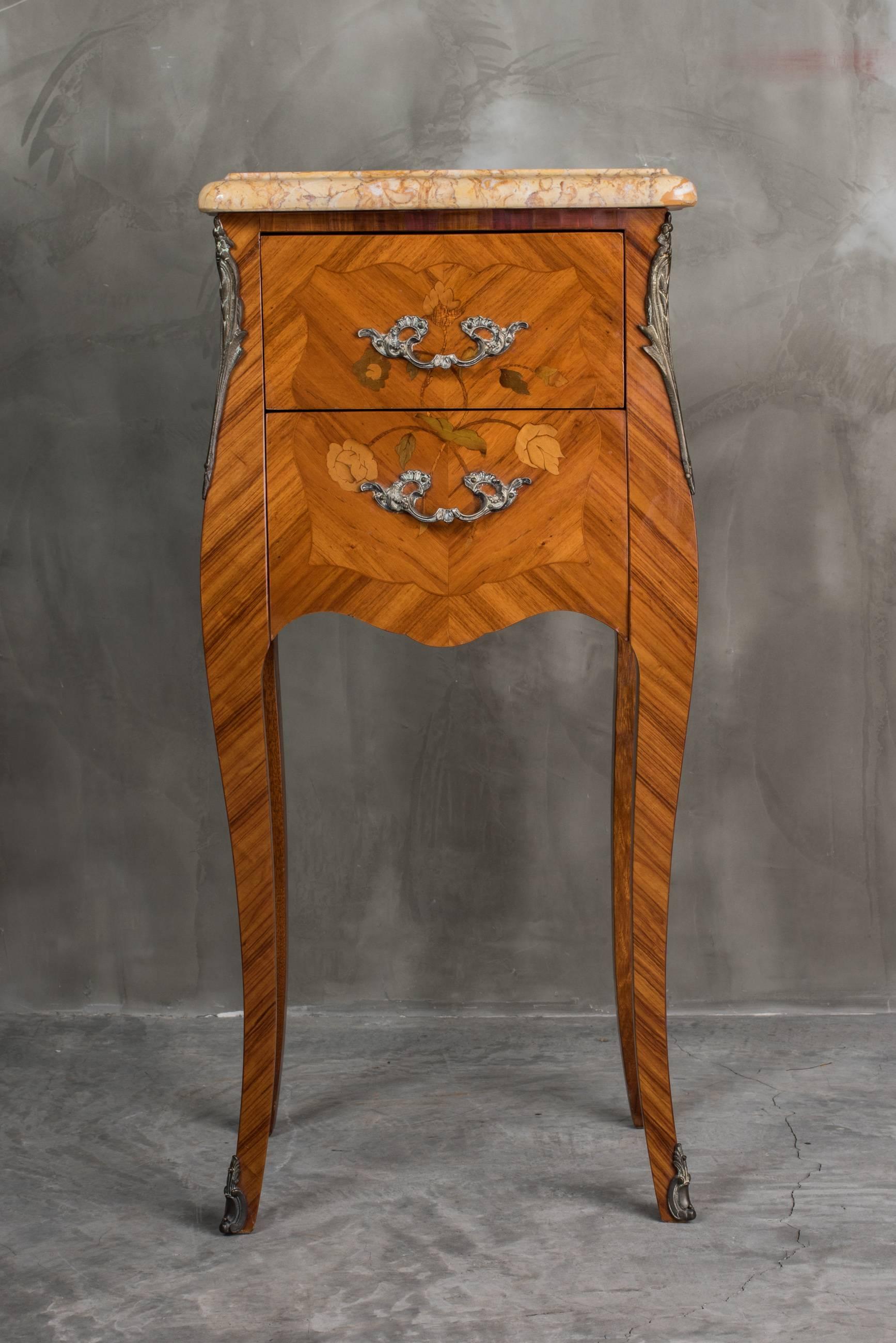 A beautiful and petite pair of Louis XV style bedside tables, found in Paris, circa 1950. In excellent condition. The marquetry in kingwood is typical of the era and the floral marquetry includes woods such as violet and rose wood. The drawers are