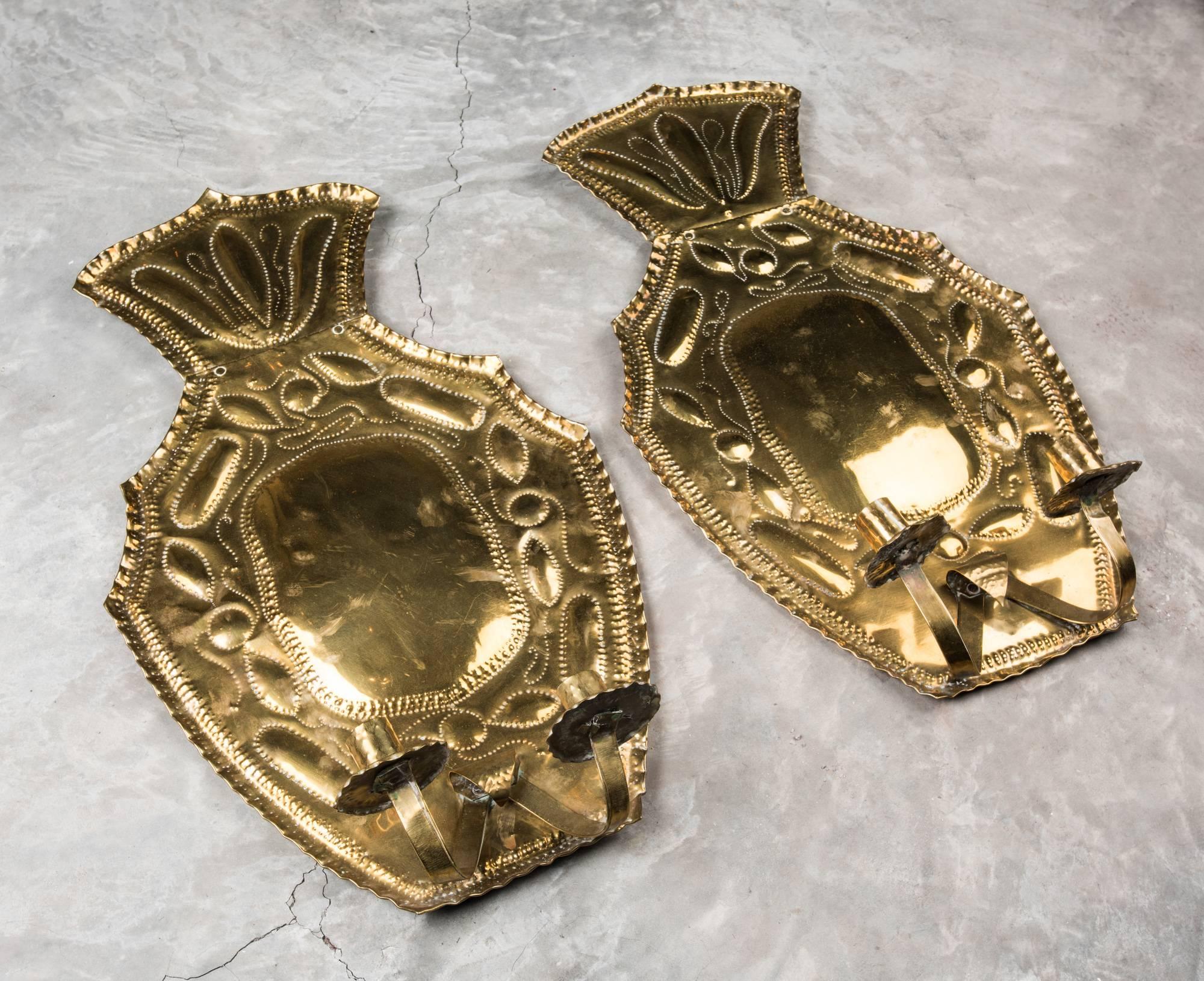 These traditional Swedish brass sconces have large brass backplates that glow with the reflected light from the lit candles. They large convex area throws golden light and the decorative patterns add special sparkles. Both sconces have two candle