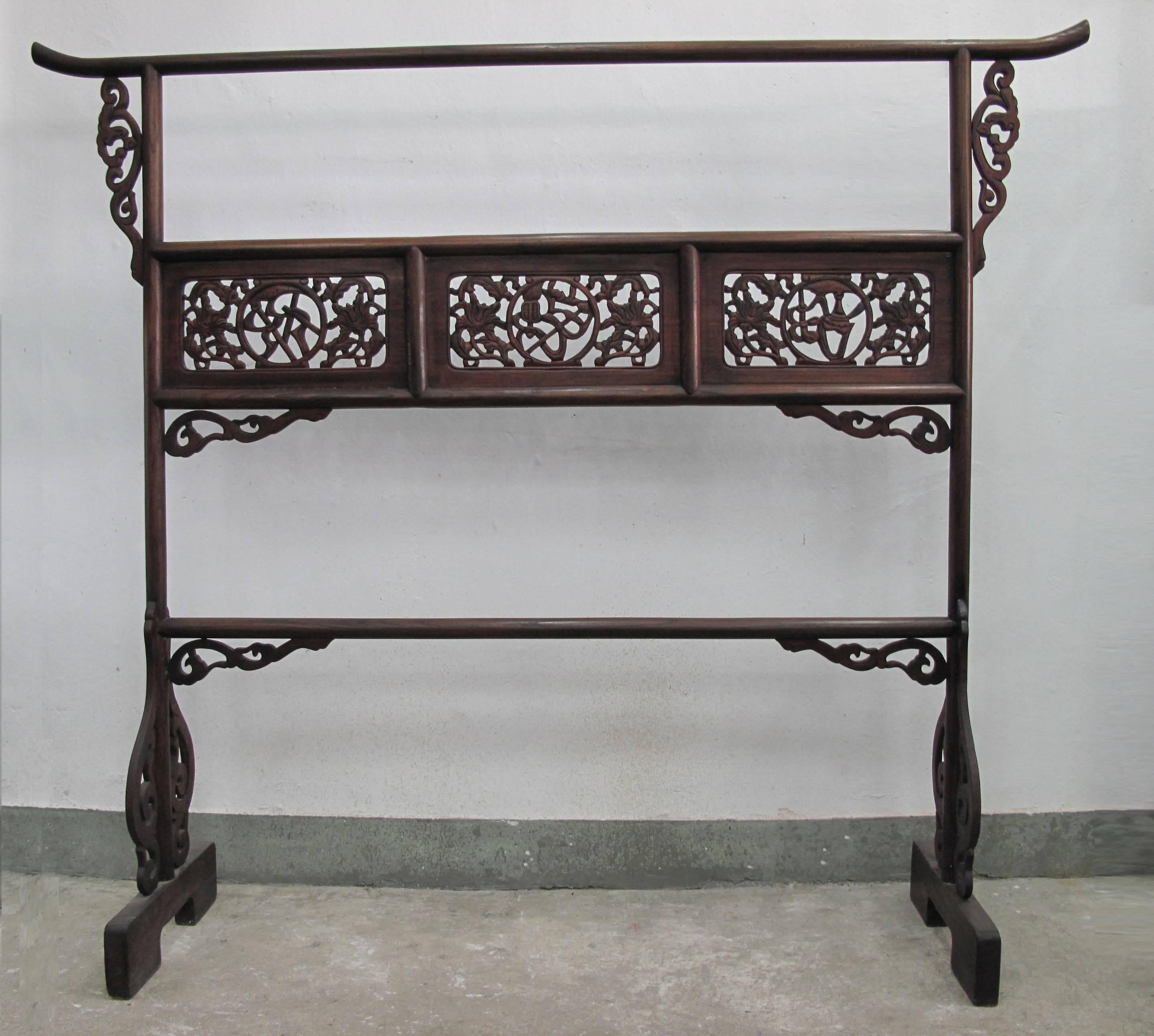 Clothes rack with upward curve-end top rail, open-work carved auspicious patterns and floral frame panel and trailing plant curve hook-end spandrel and board feet, 19th century, from Zhejiang, elmwood.