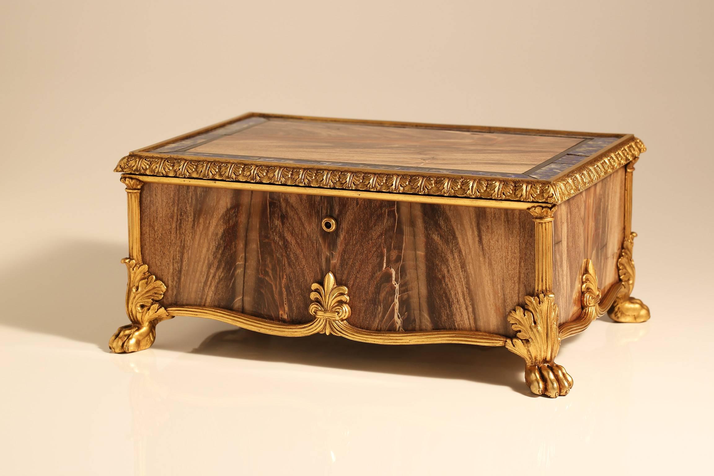 A rare and fine quality early 19th century ormolu, petrified wood and hard stone inlaid casket, probably used as a humidor. Florence, early 19th century. The hinged lifting lid with a large panel of petrified wood bordered by a lapis lazuli and