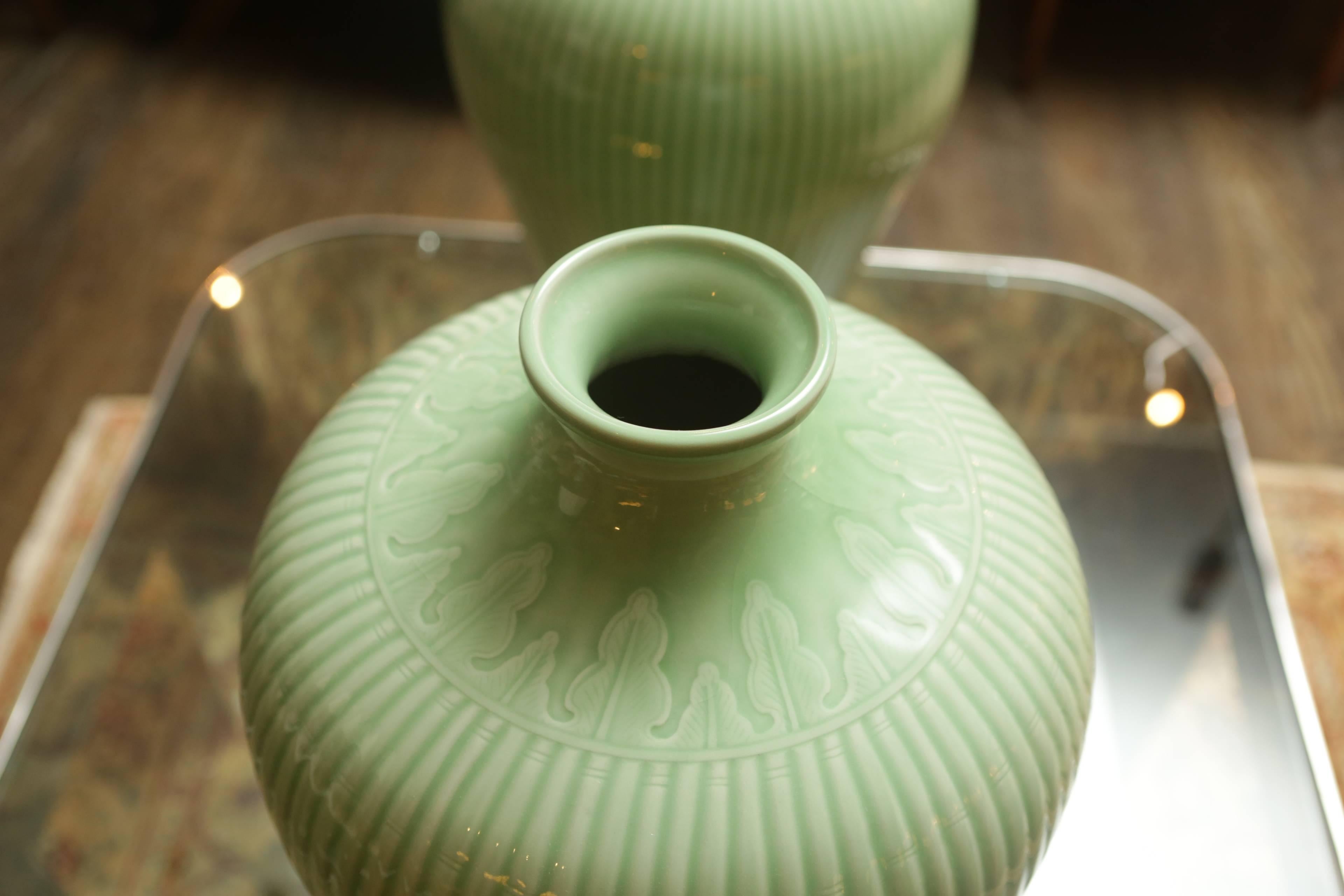 A pair of large ribbed celadon-colored glazed vases. Fluted shape and narrow opening.