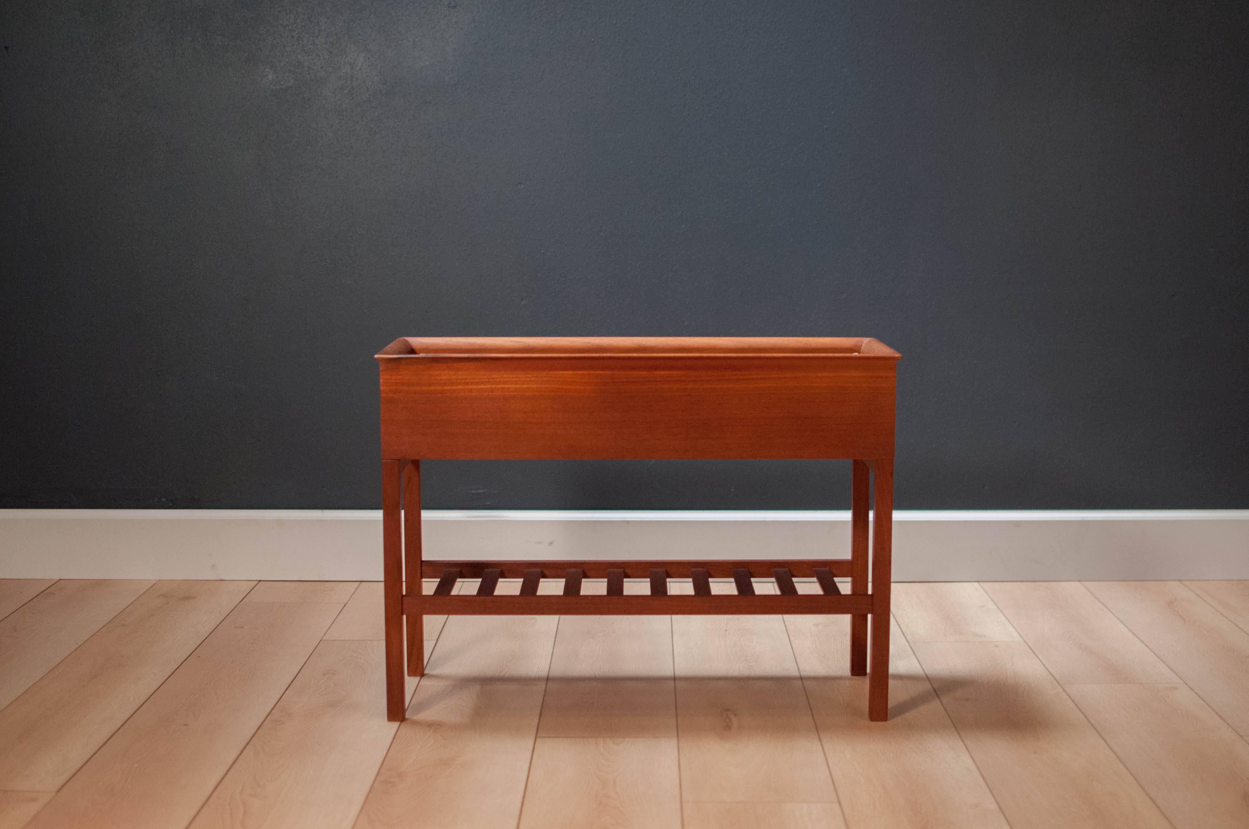 Mid-Century Danish modern planter box in teak. Features a sculpted top and magazine rack for extra storage on the bottom. Metal tray is removable. 

Dimensions: 4.5