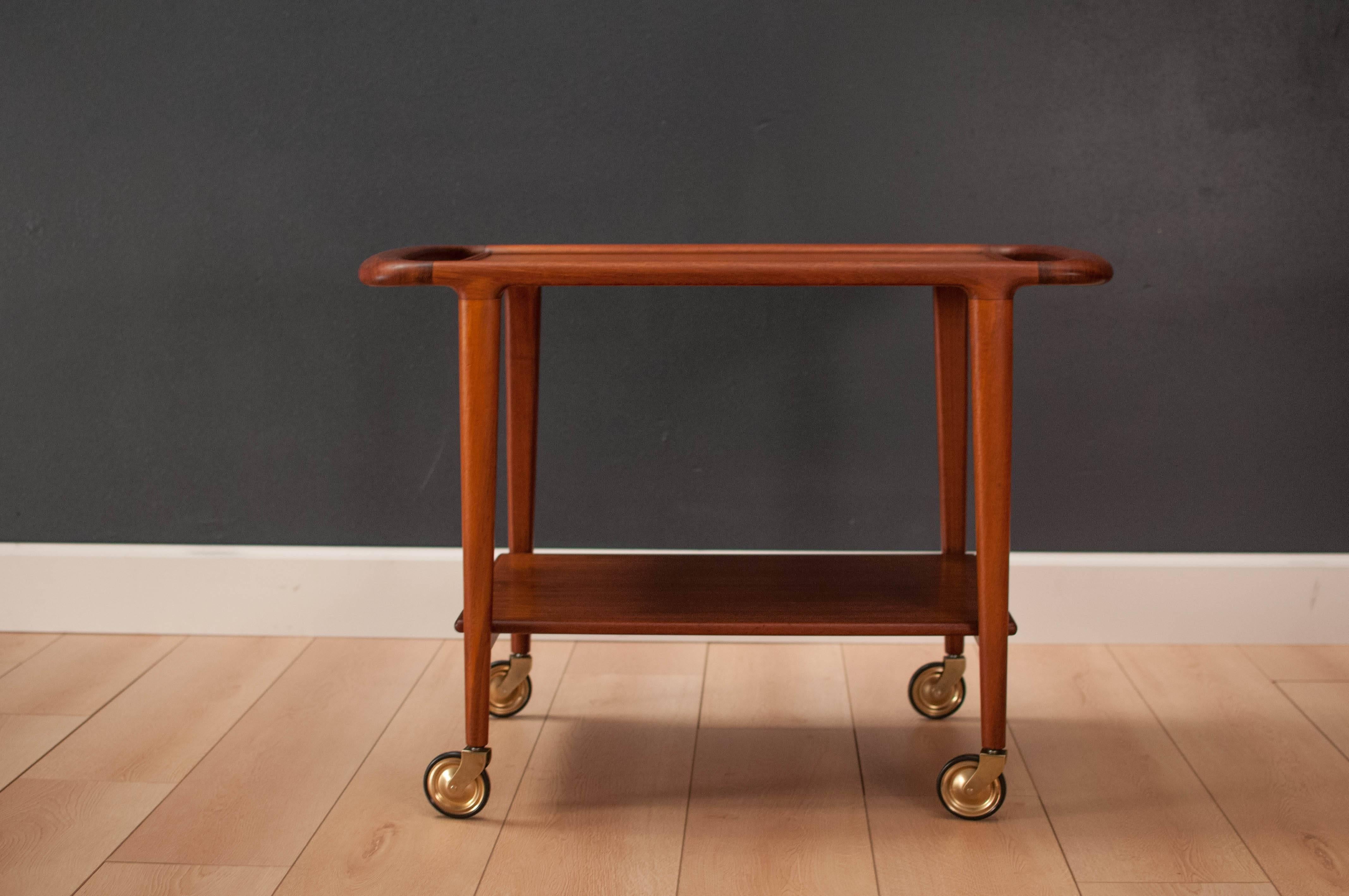 Mid-Century Modern bar cart designed by Niels Moller for J.L. Moller. This two-tier piece displays stunning teak grains and quality craftsmanship. Functions as a serving cart or rolling display tray. 

 