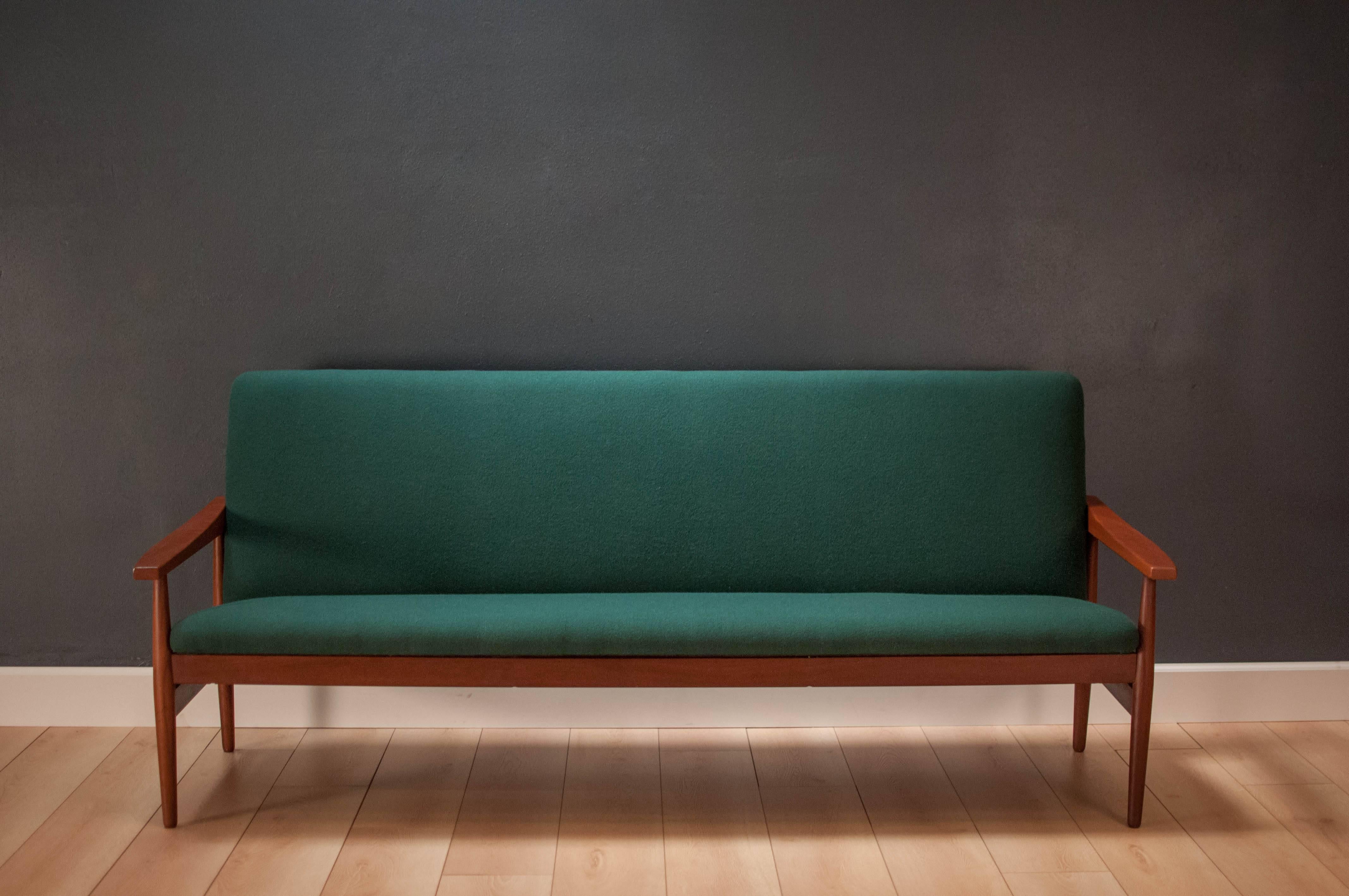 Vintage Mid-Century three-seat sofa in solid teak. This piece has been newly reupholstered in a vintage deadstock dark green wool fabric. Features a sculptural teak frame and displays well from any angle.

Dimensions: 75.5