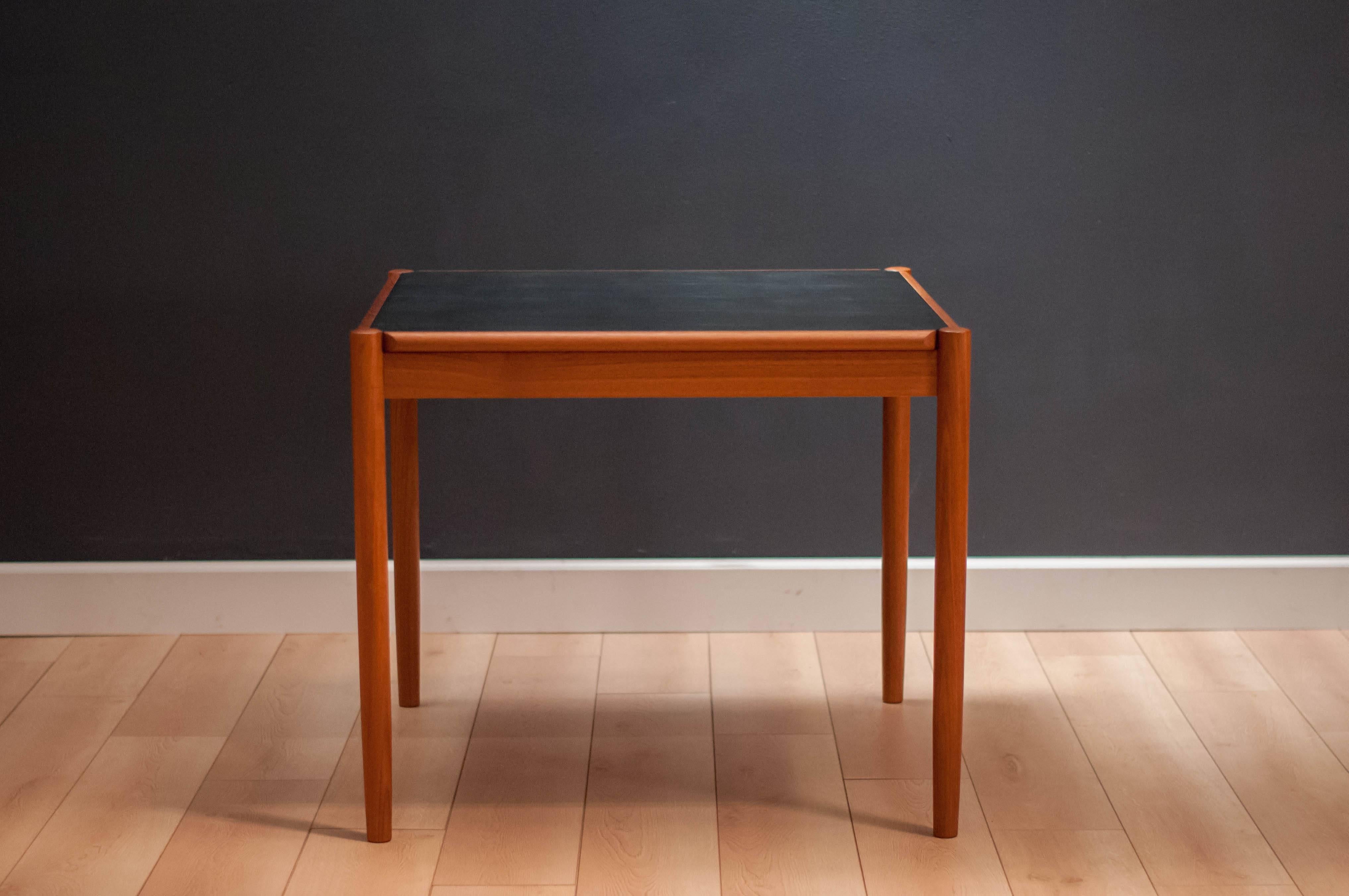 Mid-Century flip-top dining table in teak made in Denmark. This versatile piece has a reversible teak and black leather top that can function as a dining table or game table. 

  