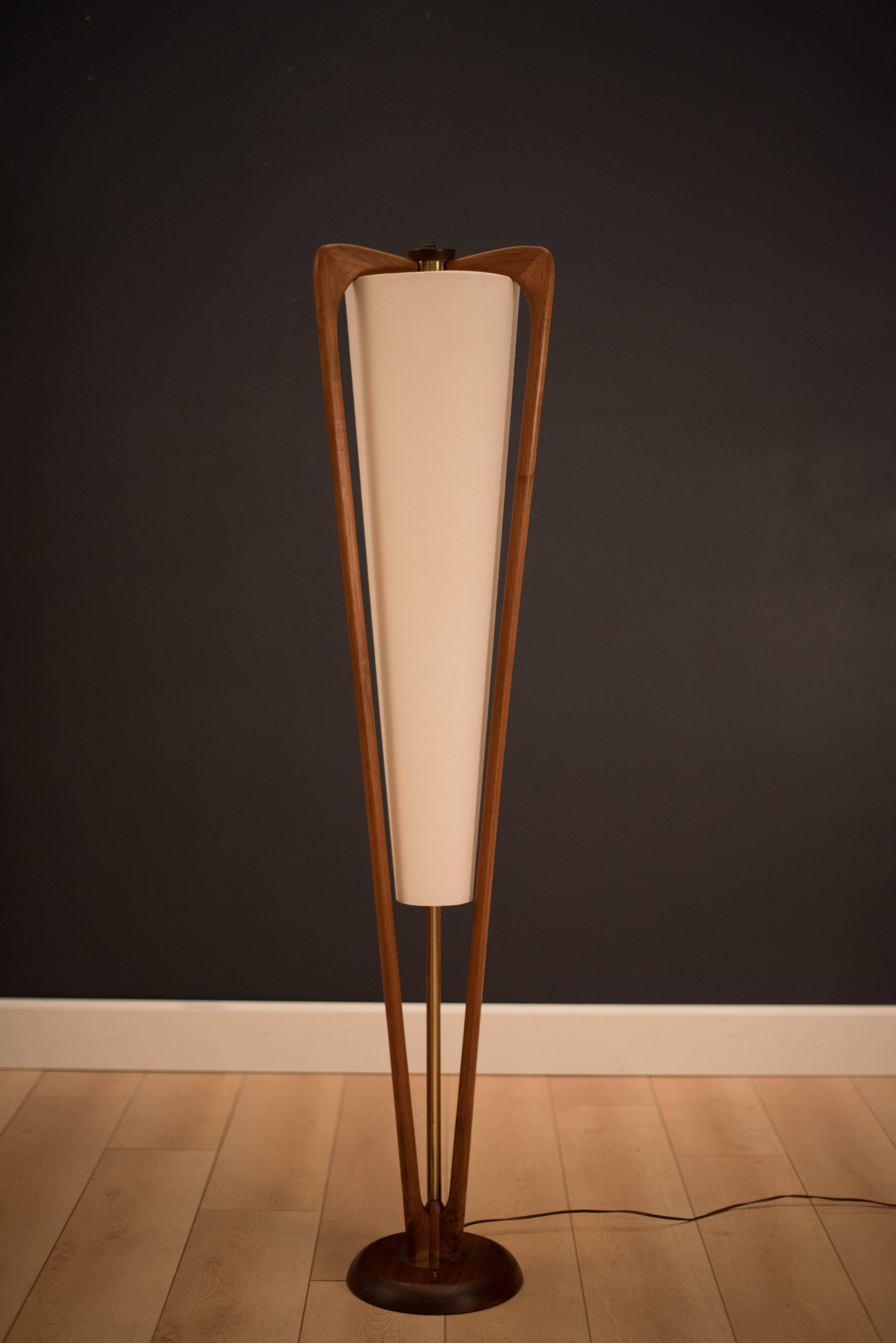 Mid-Century Modern floor lamp by Modeline in walnut. This unique piece displays a sculpted walnut frame and features a three way light switch.
 