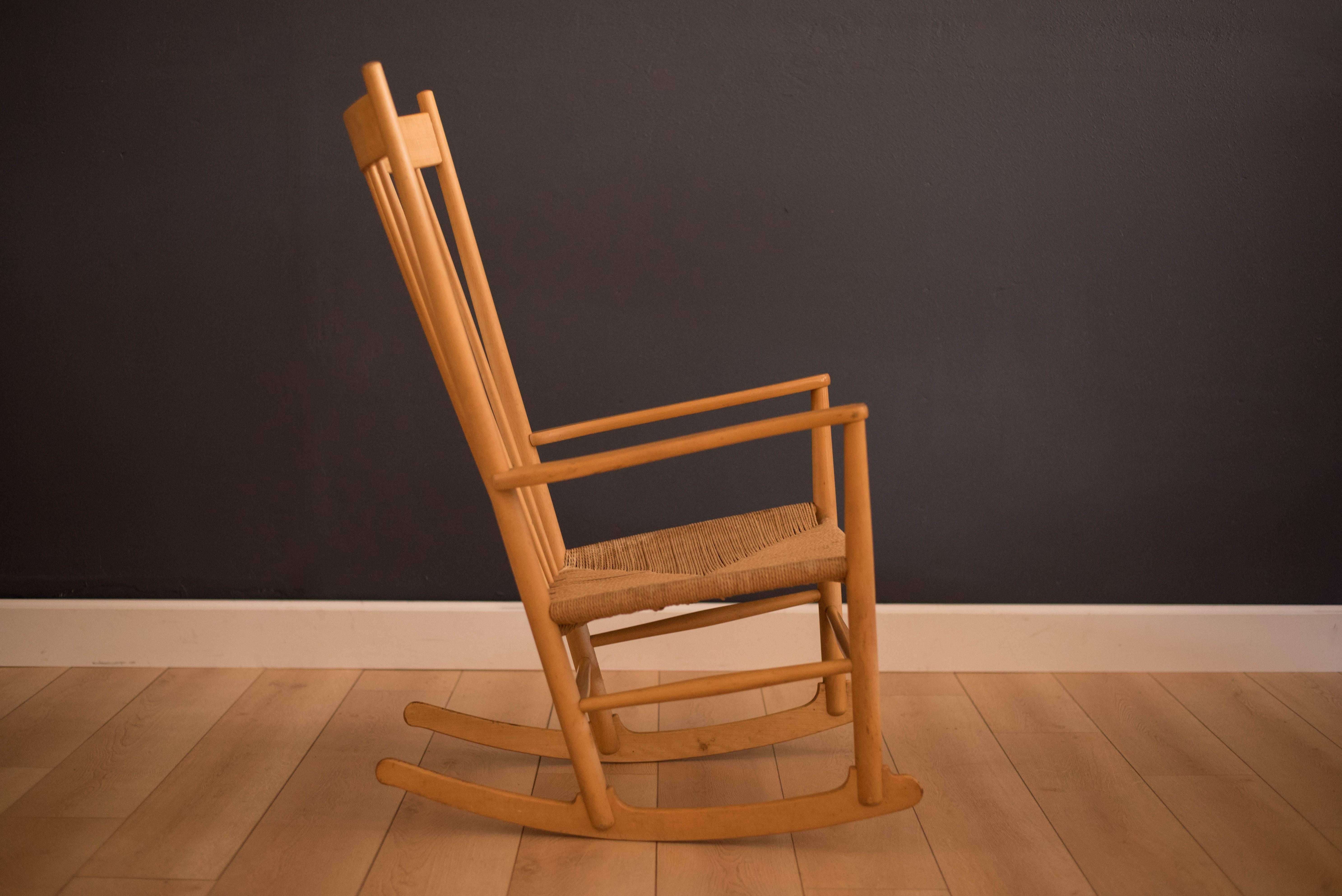 Mid-Century Danish J-16 rocking chair designed by Hans Wegner for FDB Mobler. This piece has a solid beechwood frame that displays vintage patina and woven paper cord caning is intact. 

