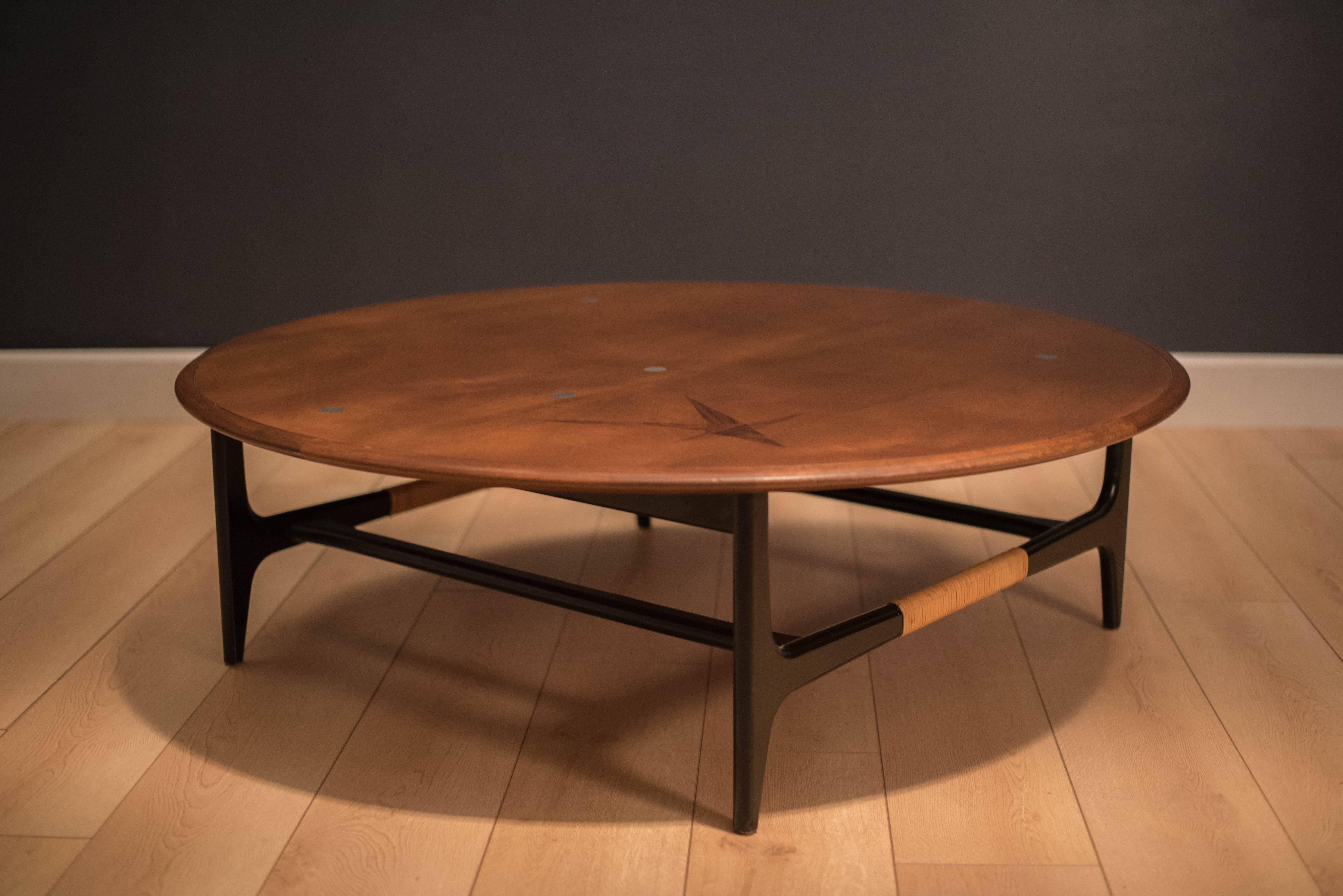 Mid-Century Modern round coffee table in walnut designed by Lane Furniture. This rare piece features a unique rosewood inlay star and round aluminium inserts. Displays cane accents on black lacquered wood base. 

 