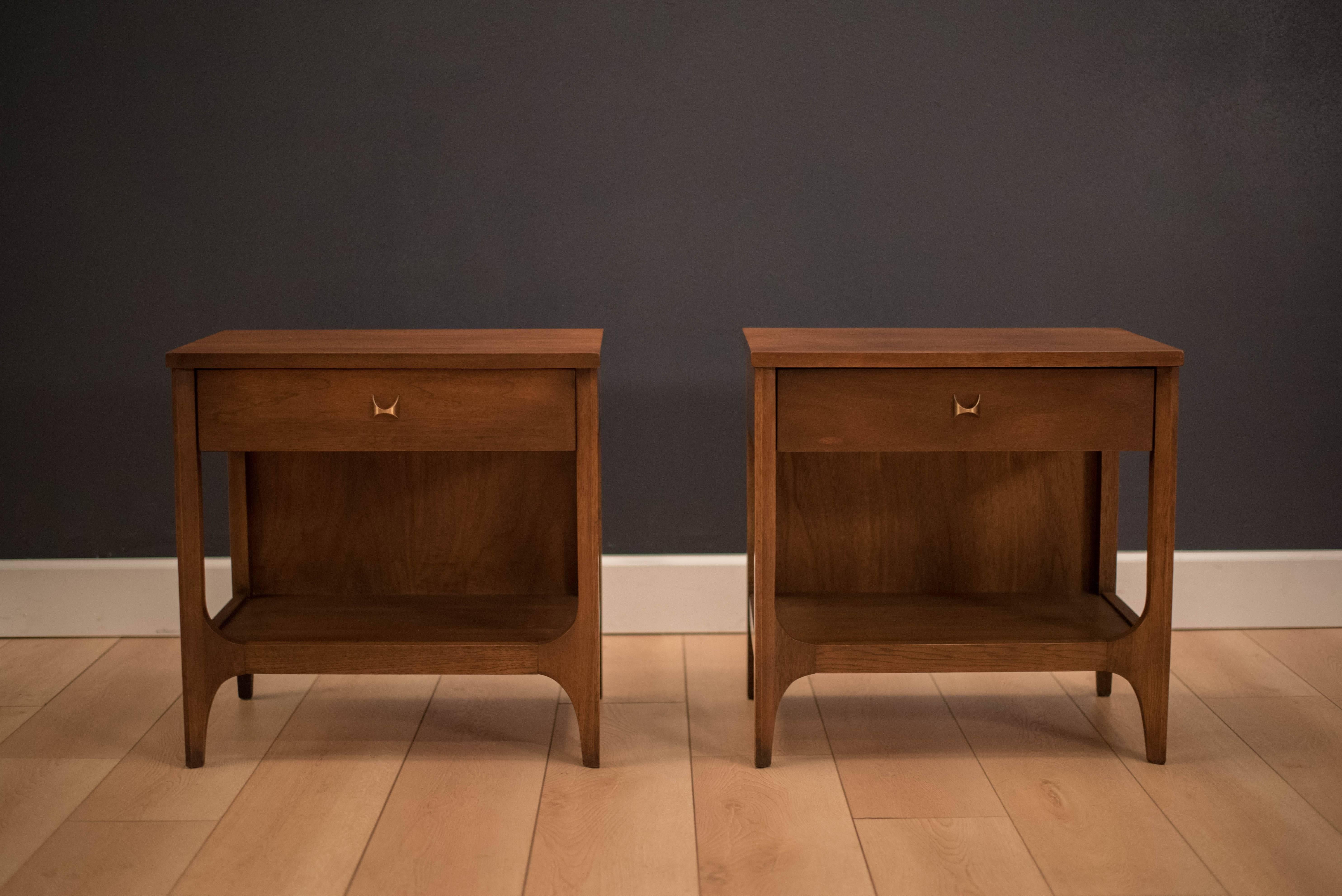 Mid-Century pair of Brasilia nightstands manufactured by Broyhill Premier, circa 1960s. This set is accessorized with the line's signature brass handles and features one pull-out drawer.

