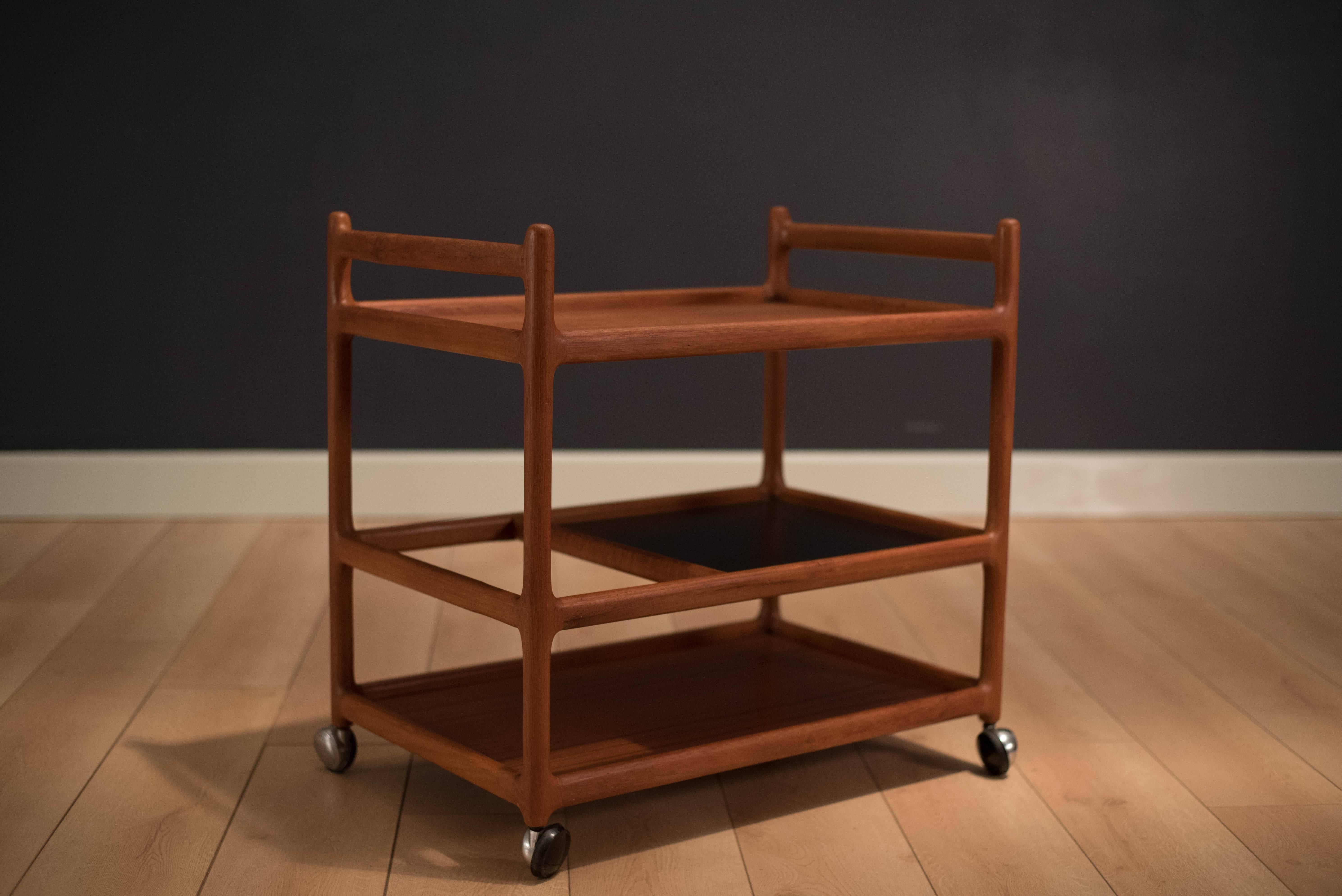 Mid-Century bar cart by Johannes Andersen for CFC Silkeborg. This multiple tiered cart is perfect for any setting. It is constructed from teak and has a black laminate surface for easy maintenance.