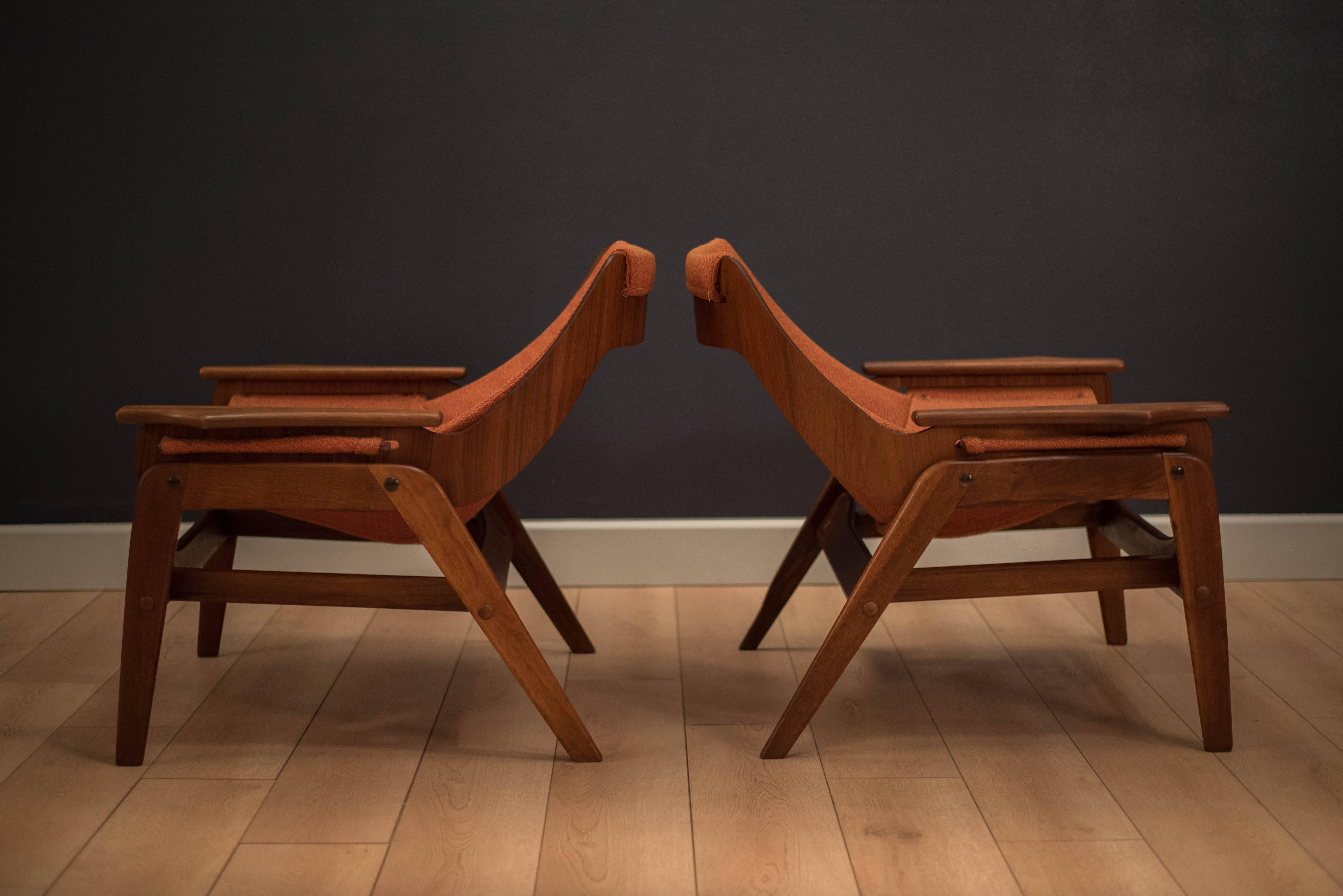 Mid-century pair of Jerry Johnson sling chairs in walnut. This matching pair features a sculptural frame and the original orange tweed sling seats. Price is for the pair. 

 