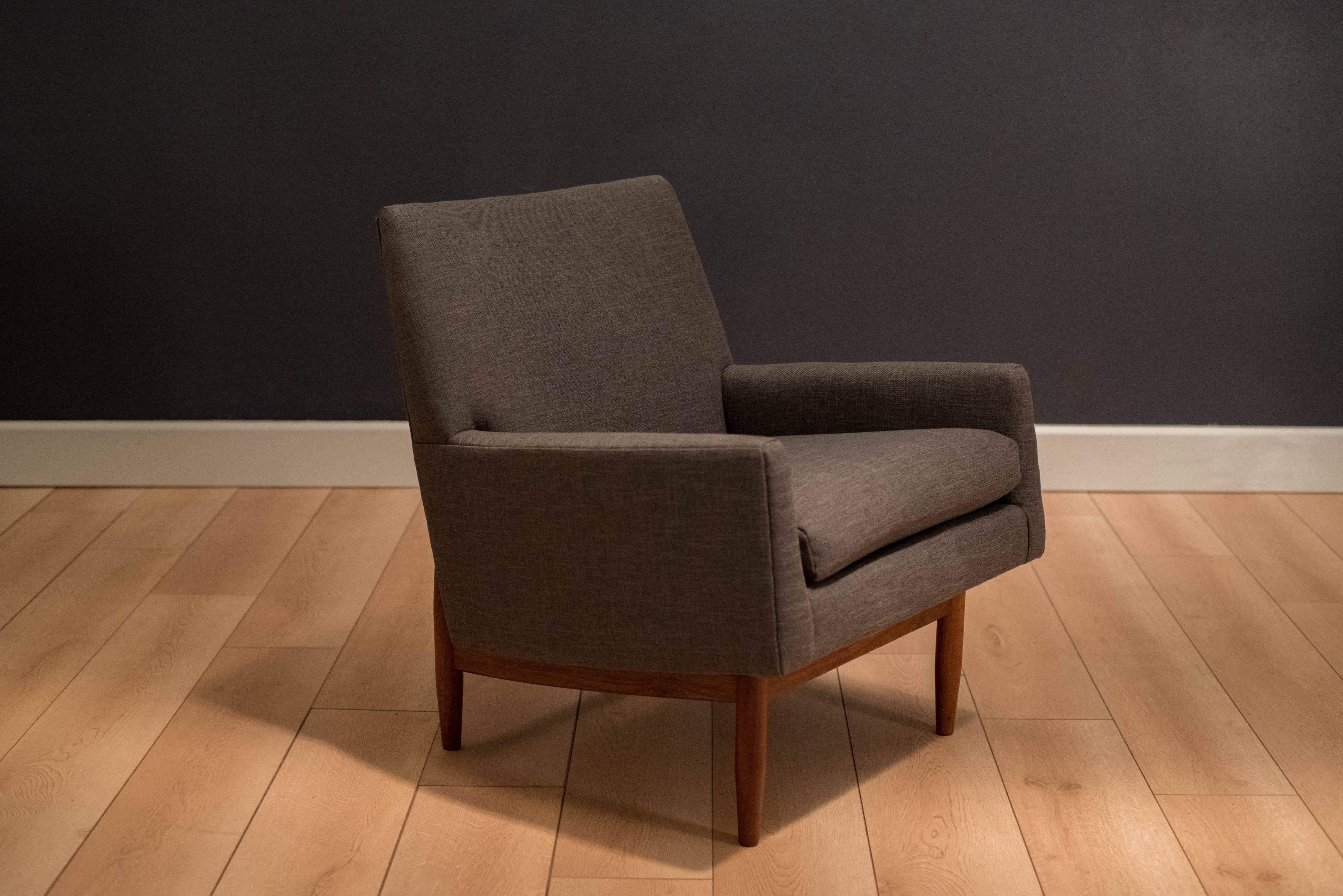 Mid-Century club chair designed by Jens Risom. This piece has a unique solid walnut frame and has been professionally reupholstered in a charcoal grey twill fabric. Displays well from any angle.

        