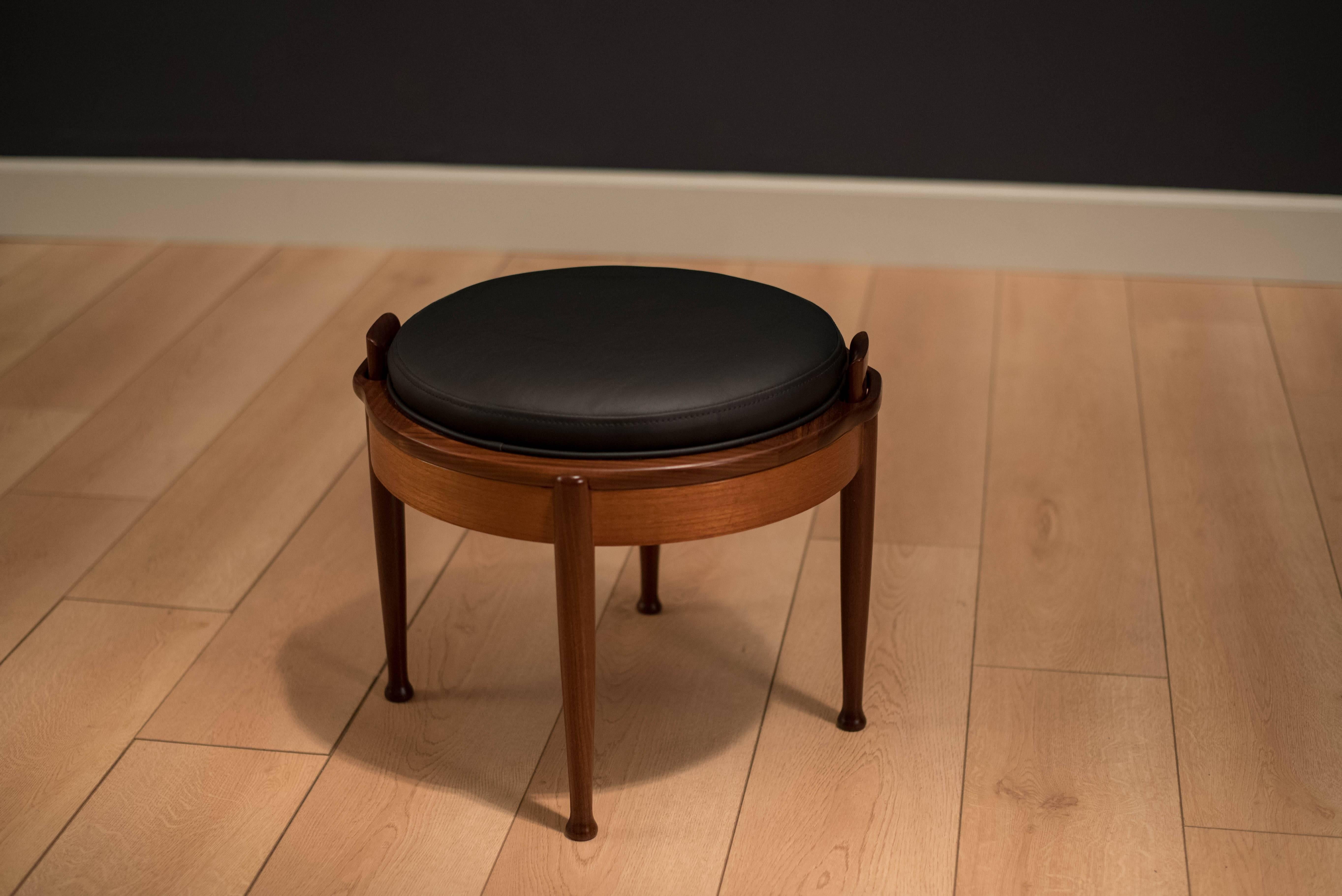 Mid-Century Modern reversible tabletop stool manufactured by B.J. Hansen. This versatile piece features a teak table top that reverses to a black vinyl seat that can be used as an ottoman or foot stool. 

  