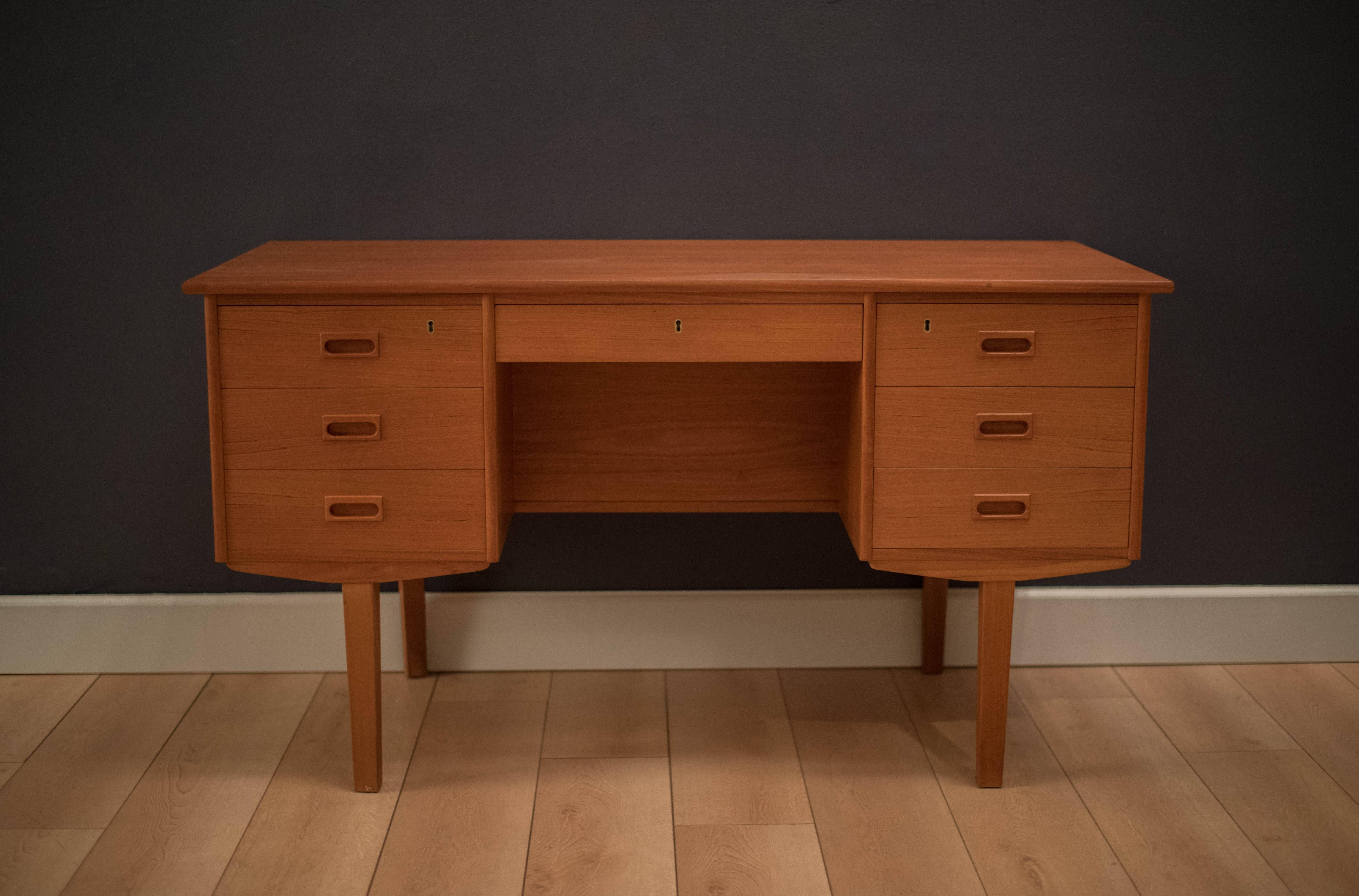 Mid-Century Danish modern desk in teak, circa 1960s. This piece comes with seven dovetailed drawers and a finished bookshelf display. Skeleton key not included.

