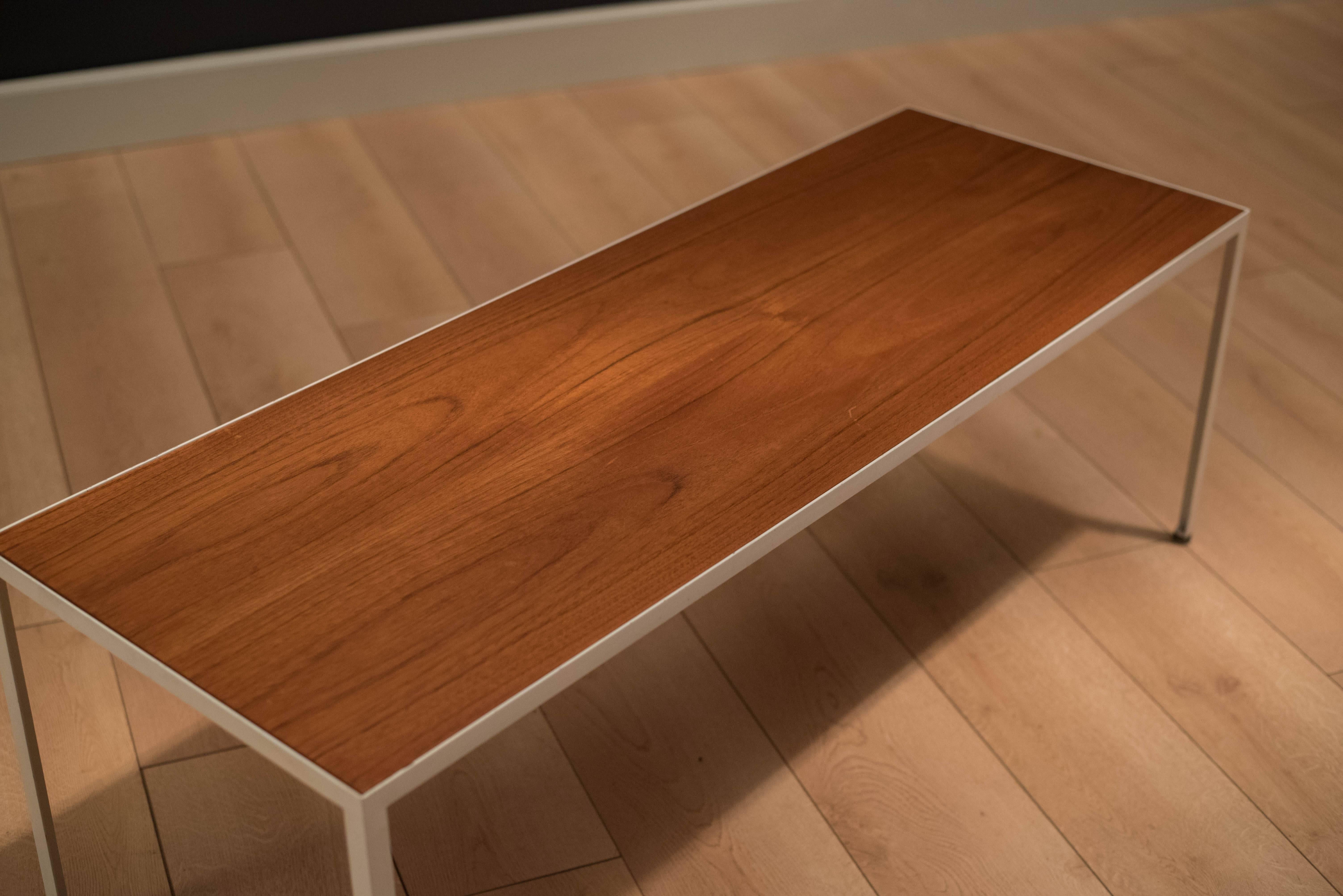 Mid-Century coffee table by George Nelson for Herman Miller model no. 5150. This piece has a teak tabletop with a contrasting white coated enameled steel base.

          