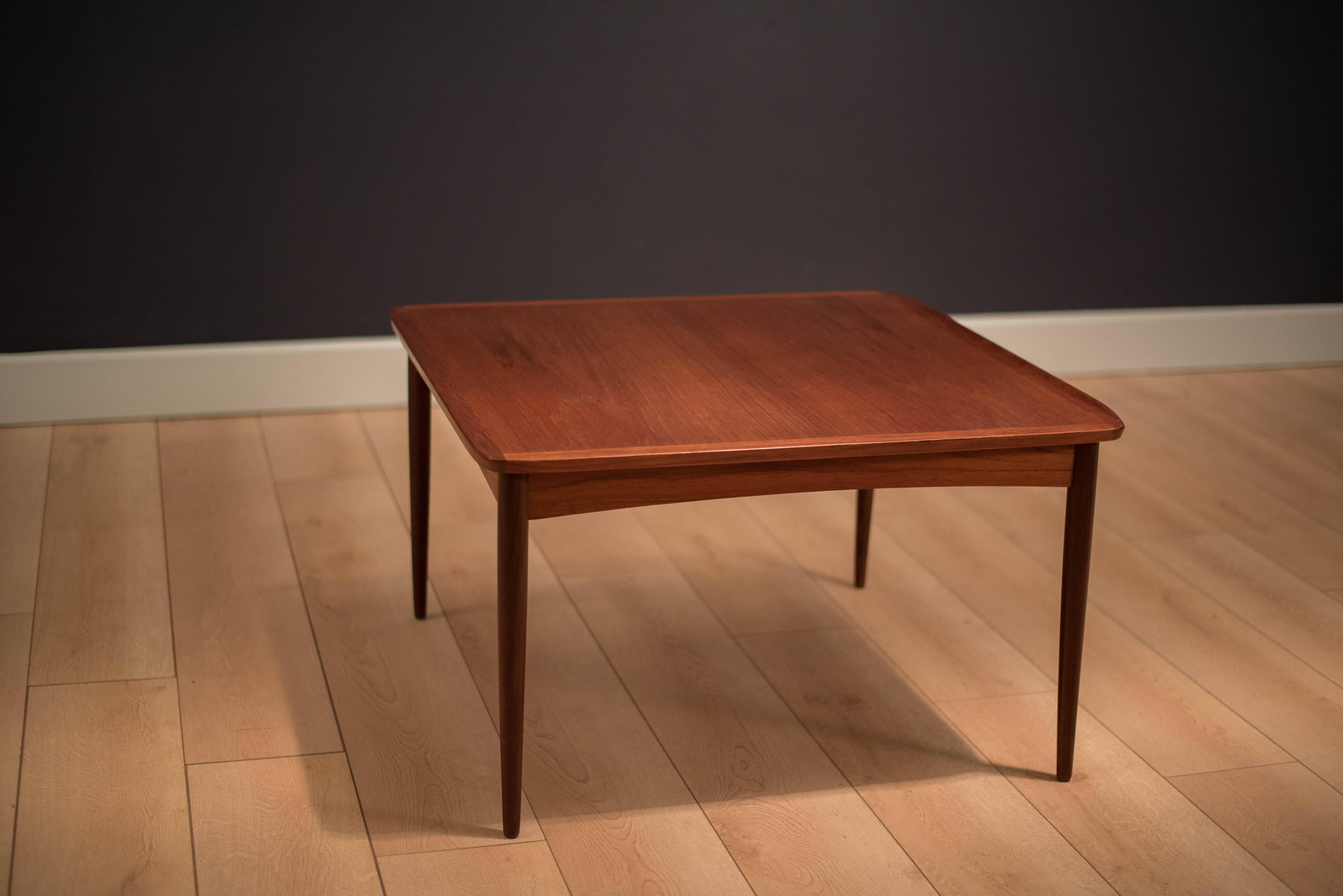 Mid-Century Modern teak square coffee table manufactured by Mobelintarsia. This piece features sculpted raised edges and sleek tapered legs. 

 