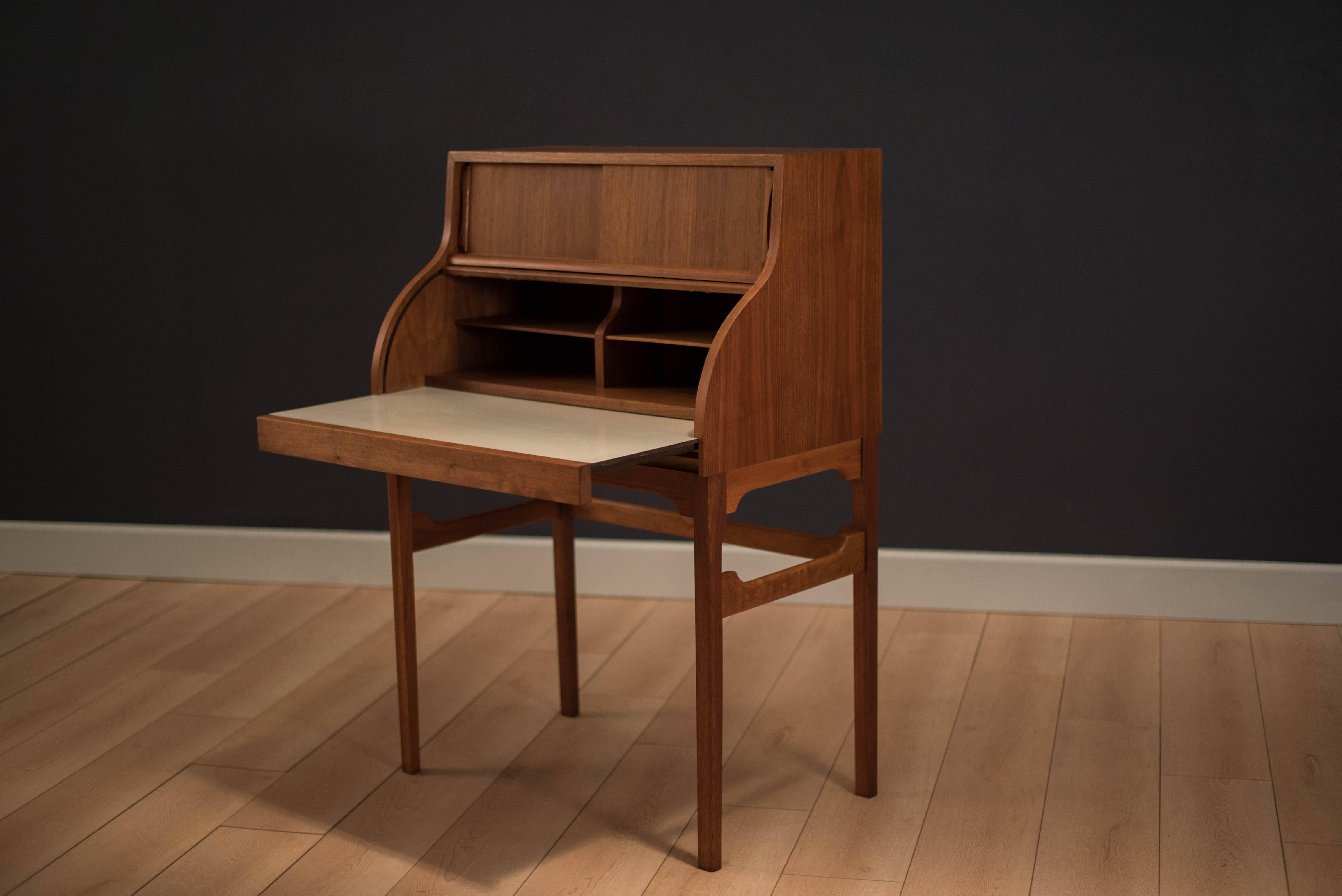 Mid-Century roll top desk by Brown Saltman in walnut. This piece features a pull out laminate desktop and tambour door that simultaneously rolls up. Sliding doors reveal open storage space. 


