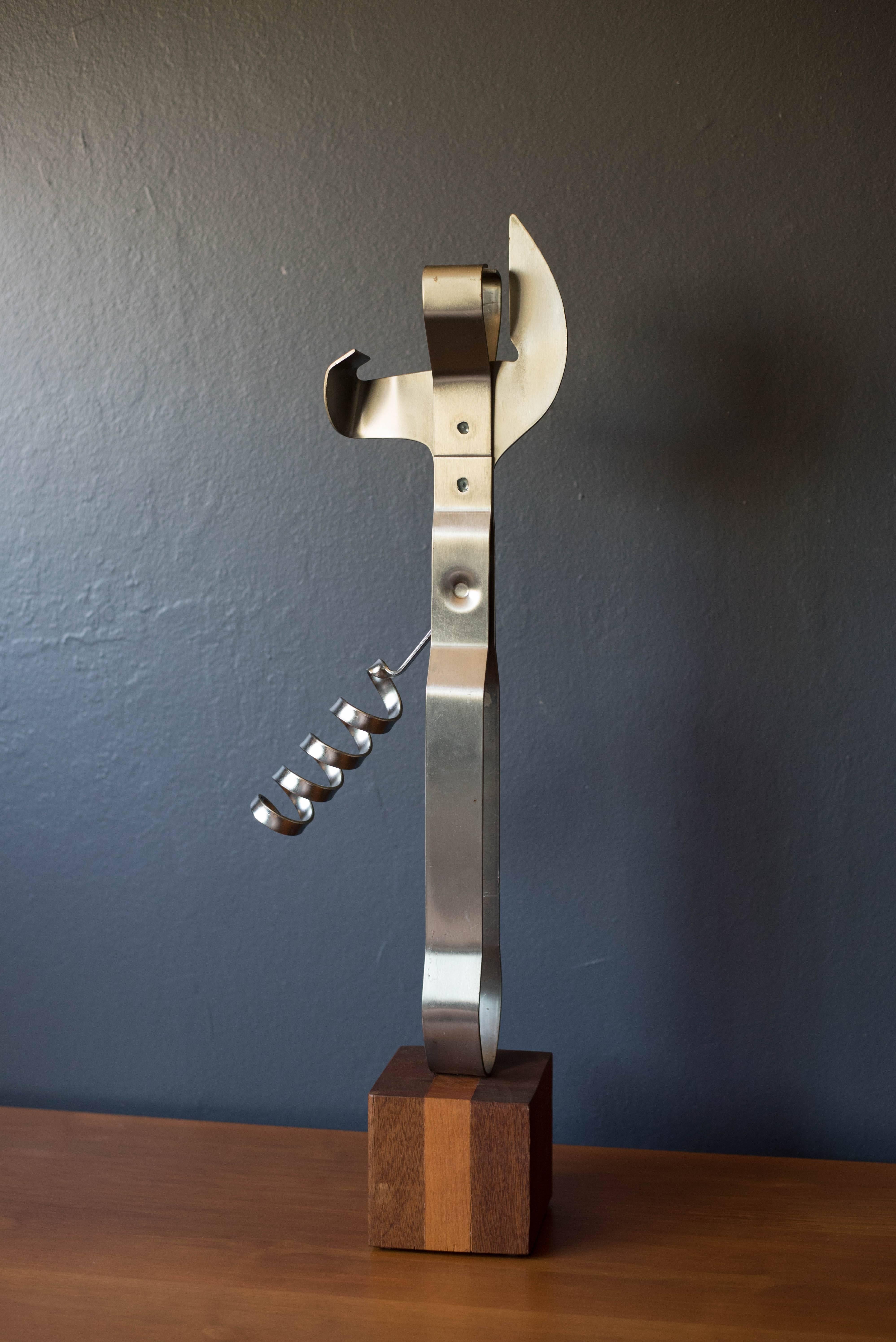 Vintage corkscrew can opener sculpture by Curtis Jere, Artisan House, circa 1979. This piece is made of chrome plated steel and sits on a wood base. 

 
