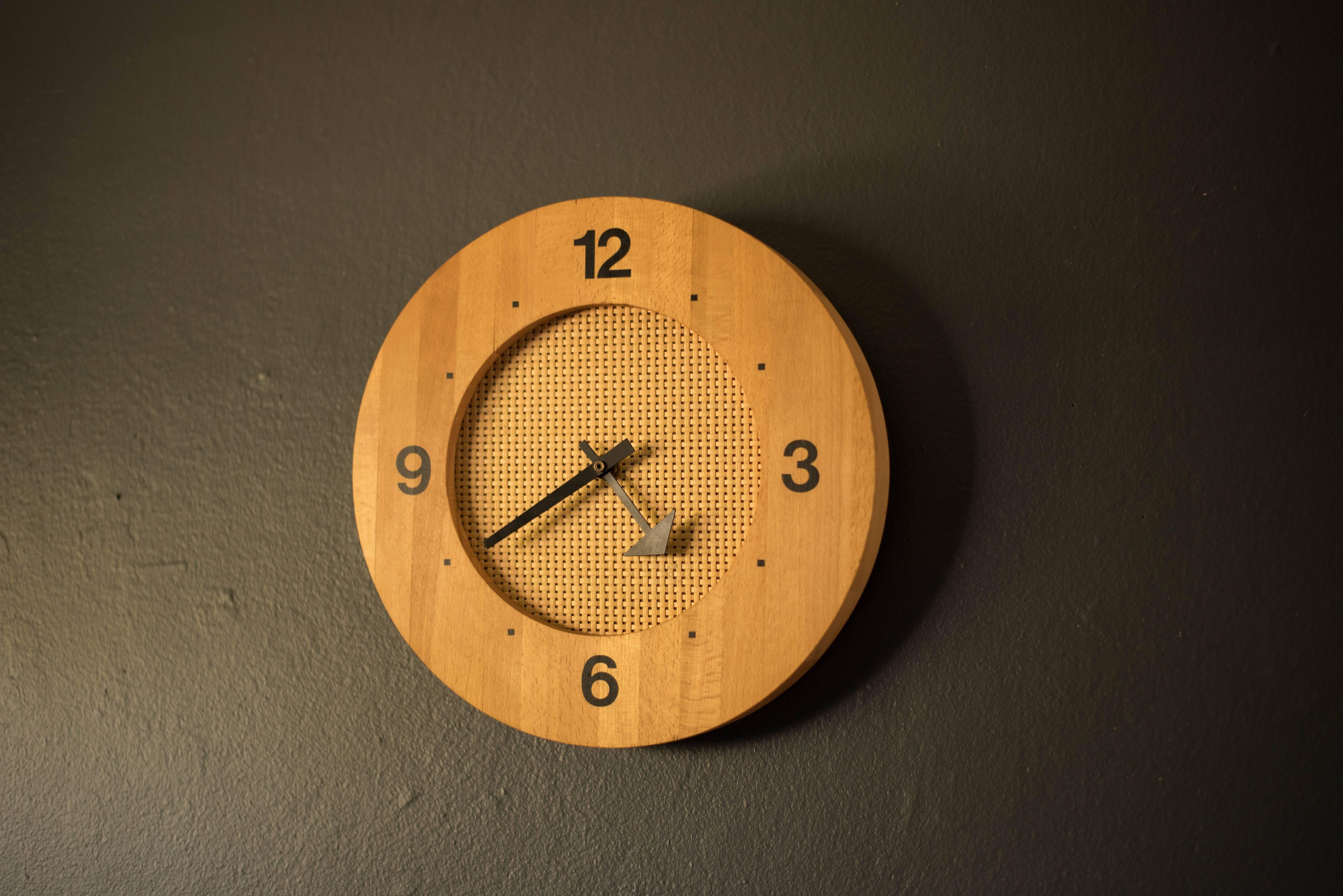 Mid-Century Modern clock in wood and cane accents, circa 1960s. This piece displays modern hands in the style of George Nelson. 

 