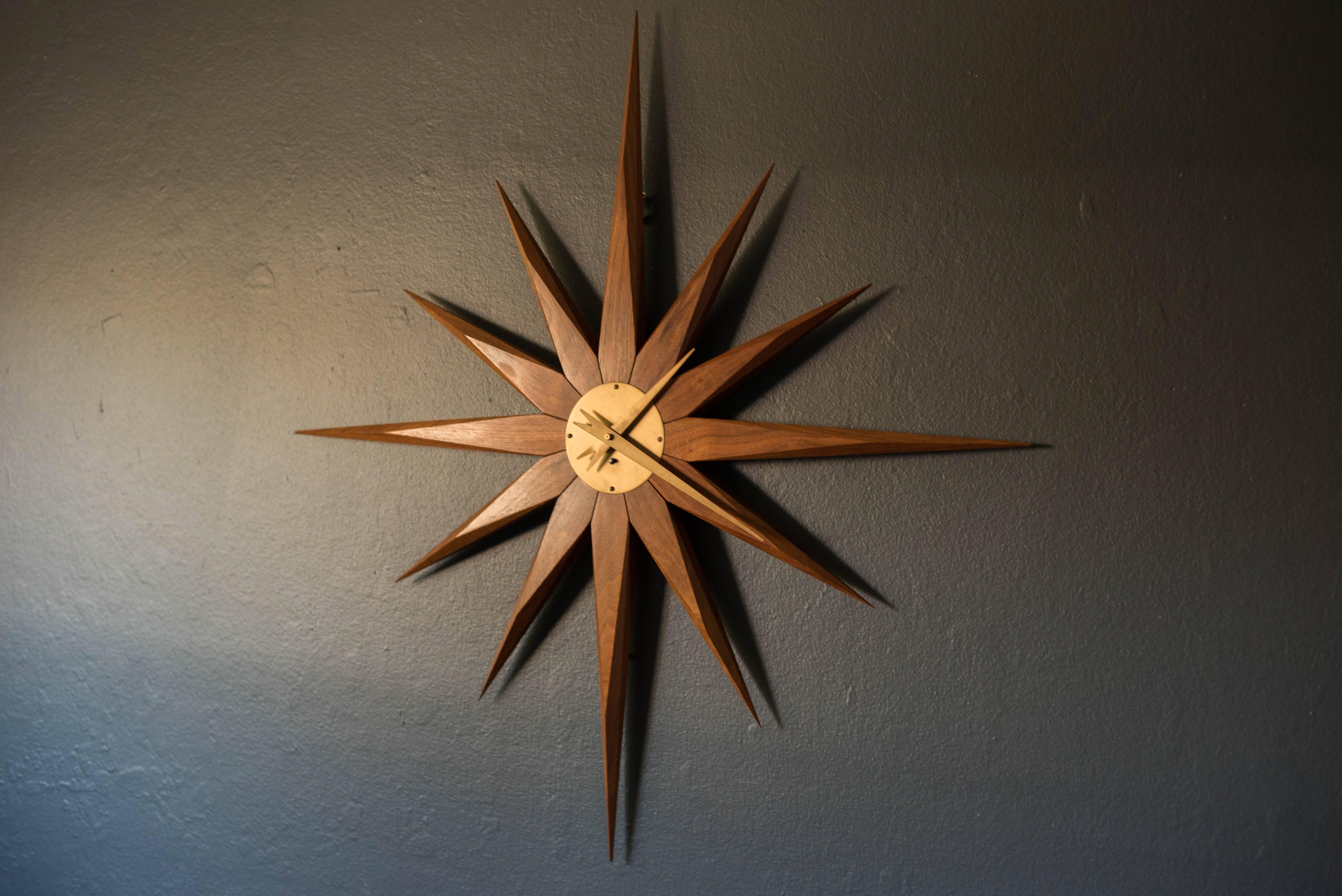 Mid-Century starburst clock in solid walnut and brass. This piece is complete with the original wind-up mechanism and key. 

 