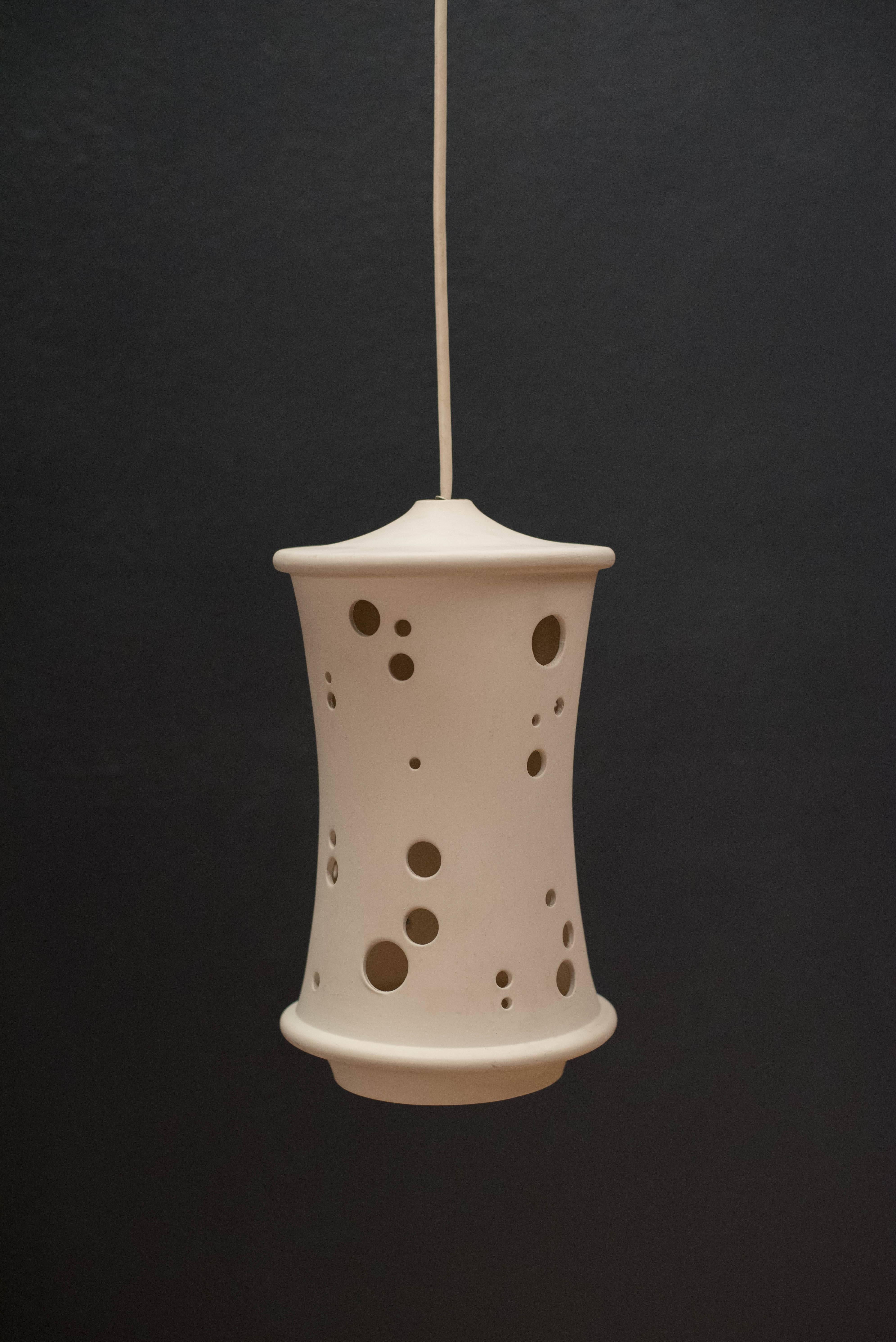 Mid-century stoneware pendant fixture, circa 1960s. This piece features a unique shape in a white ceramic finish that illuminates when lit up.

 