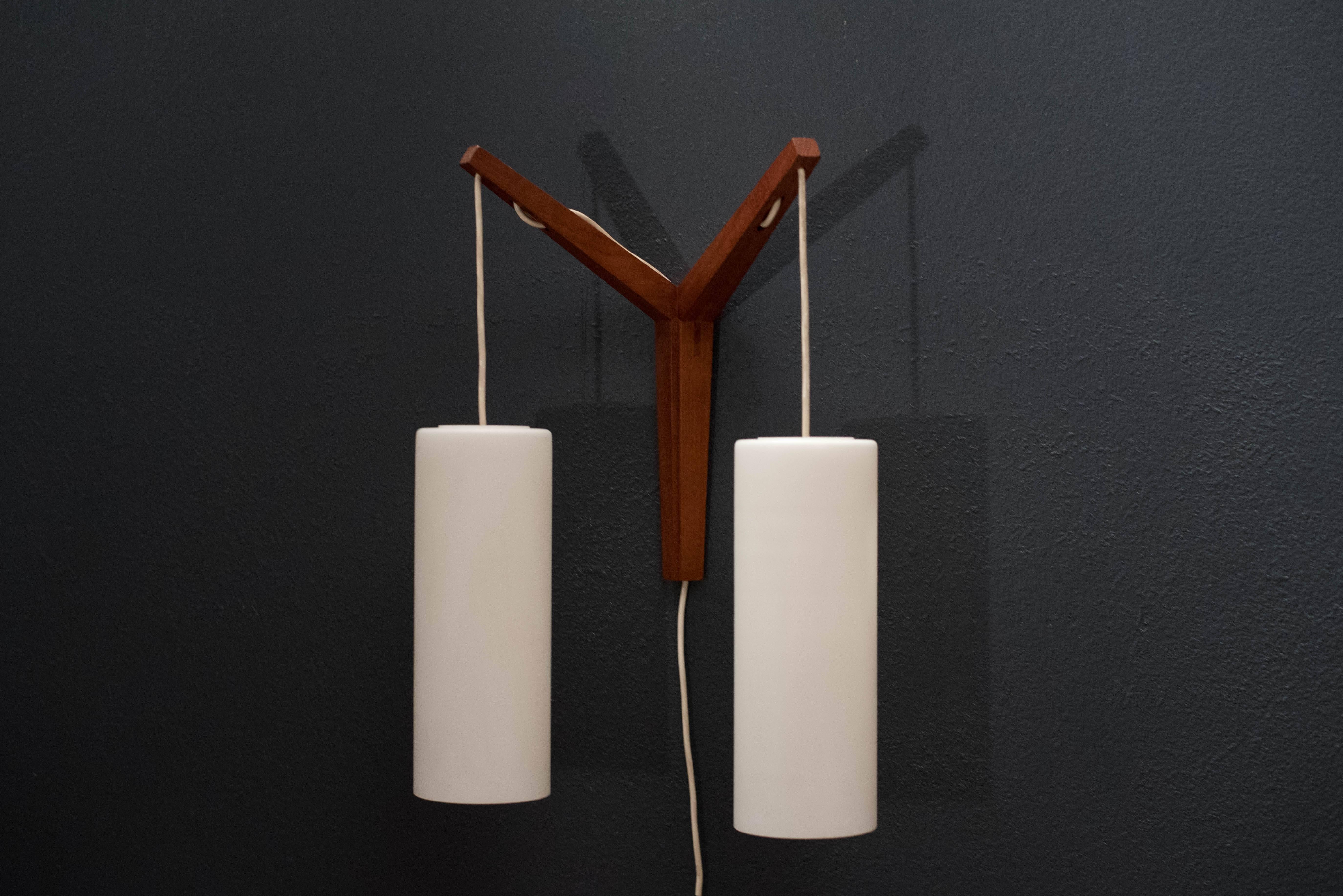 Vintage Scandinavian teak wall mount light fixture, circa 1960s. This piece includes two hanging white pendants with frosted white glass shades. 

 