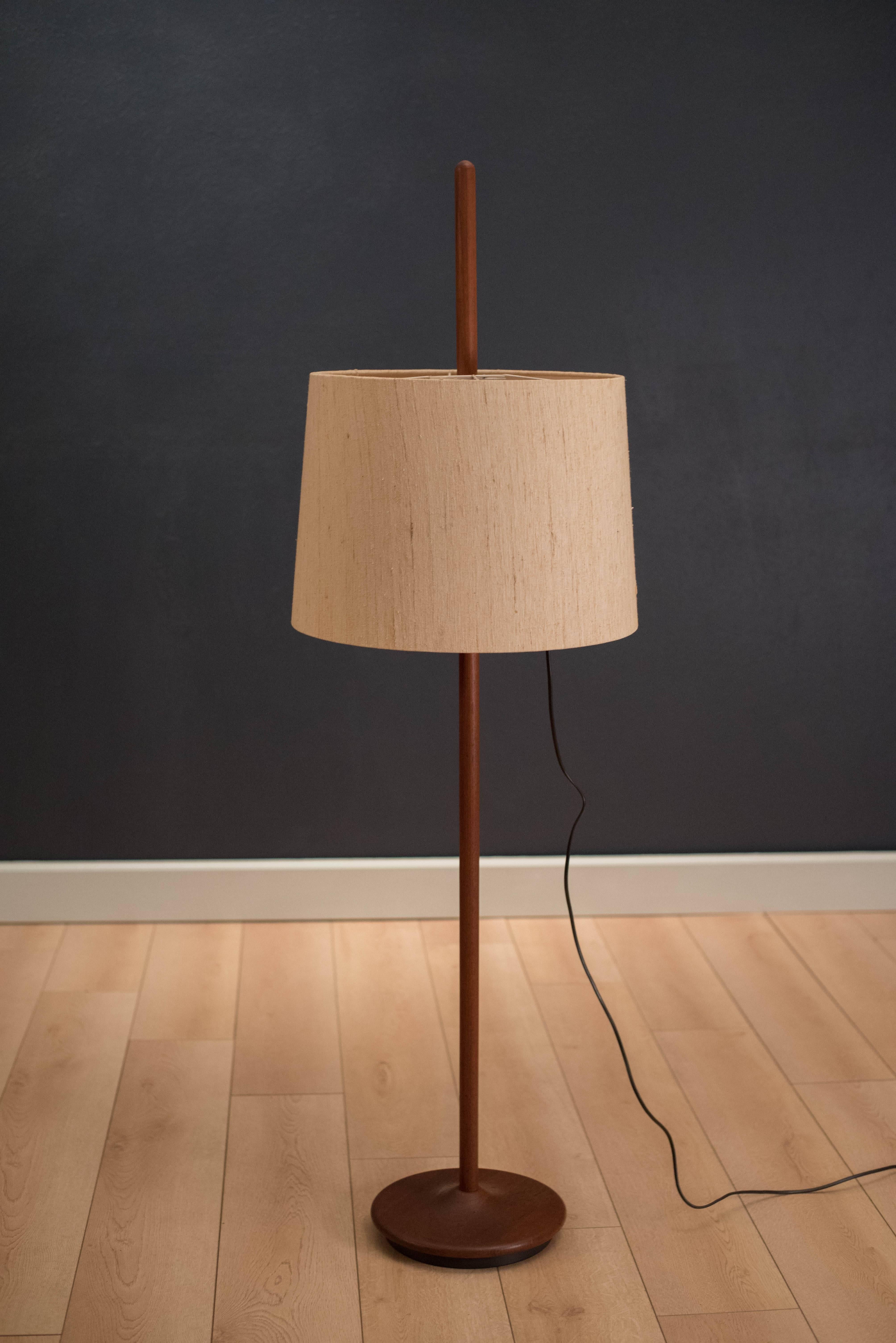 Midcentury adjustable floor lamp in teak. The shade can easily be adjusted to any position along the pole. 

  