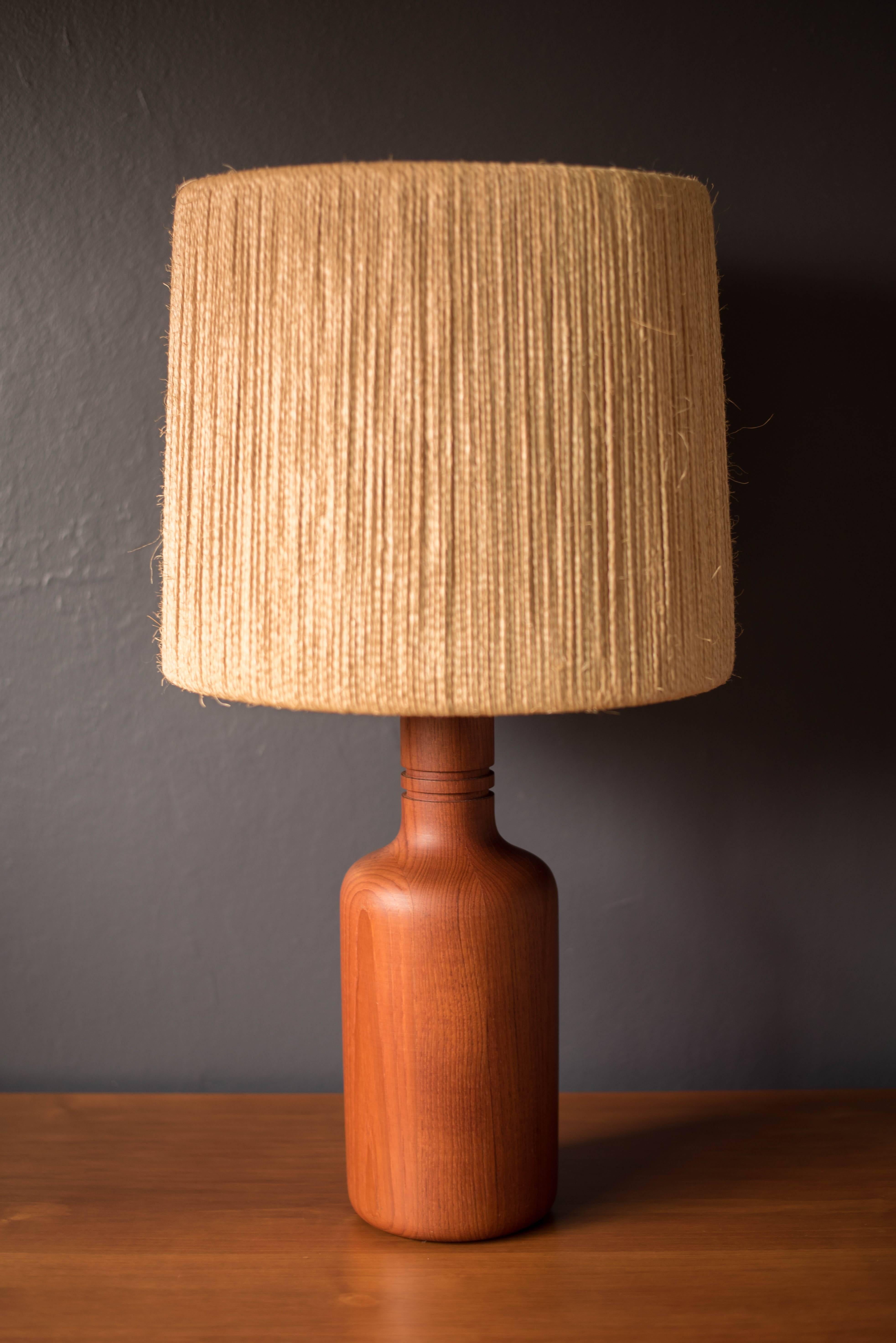 Mid-Century lamp designed by Fog & Mørup in solid teak. This piece includes the original jute string shade and cover.
 