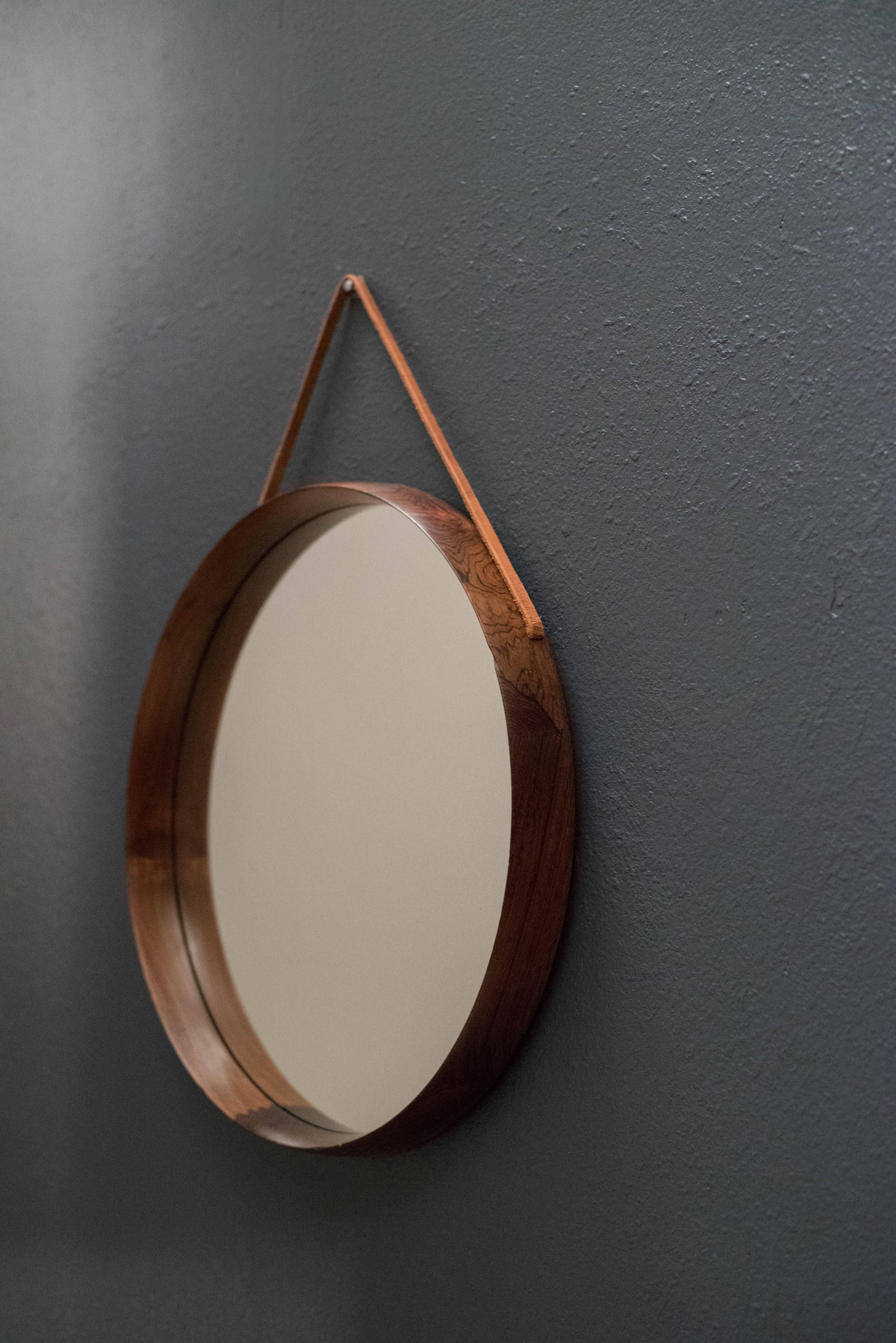 Vintage round mirror designed by Uno & Östen Kristiansson for Luxus of Sweden. This piece is includes a rosewood frame with detailed joinery and a leather hanging strap.

 