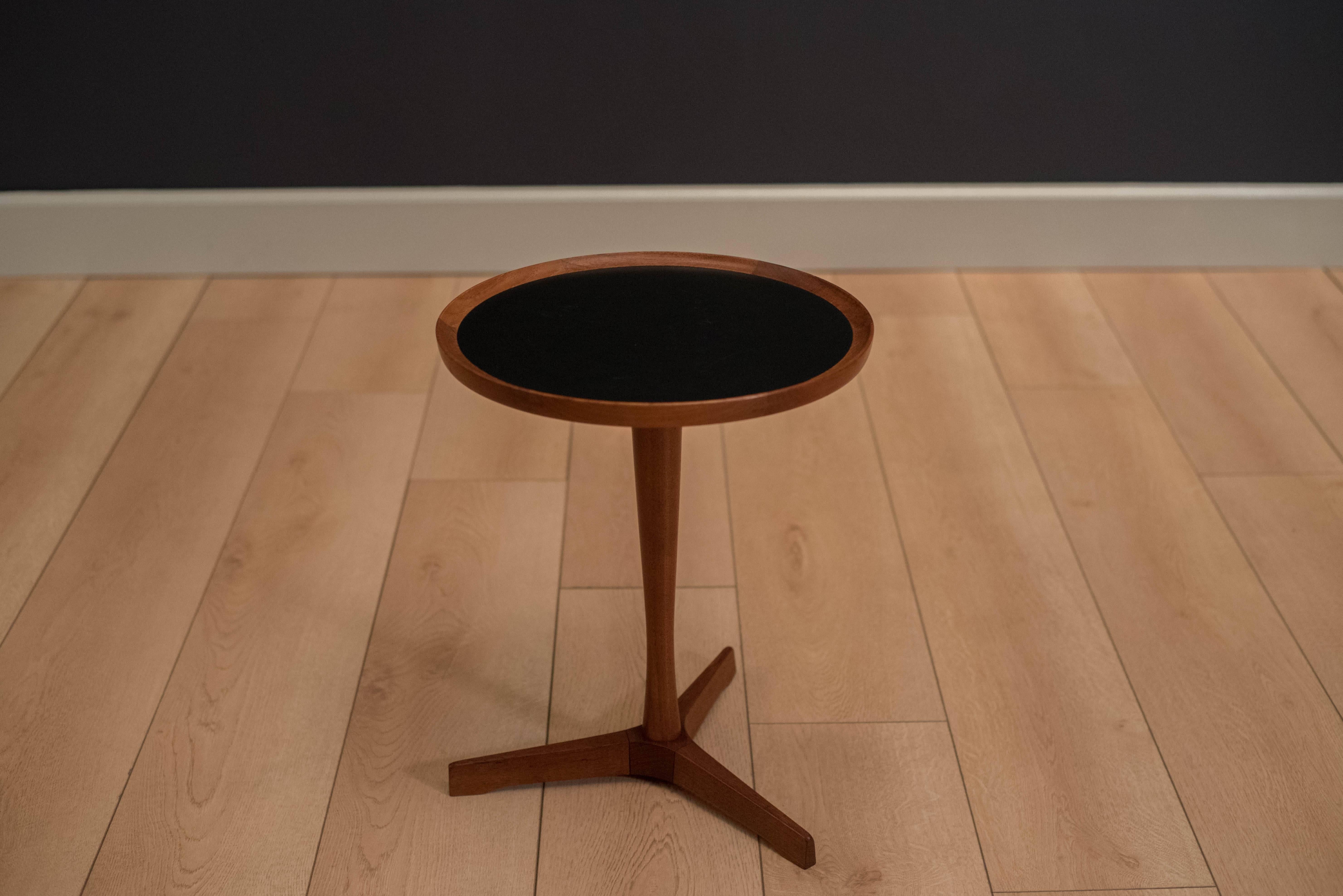 Mid-Century Modern pedestal side table designed by Hans C. Andersen for Artex. This piece has a black laminate inlaid top and a solid teak base. 

