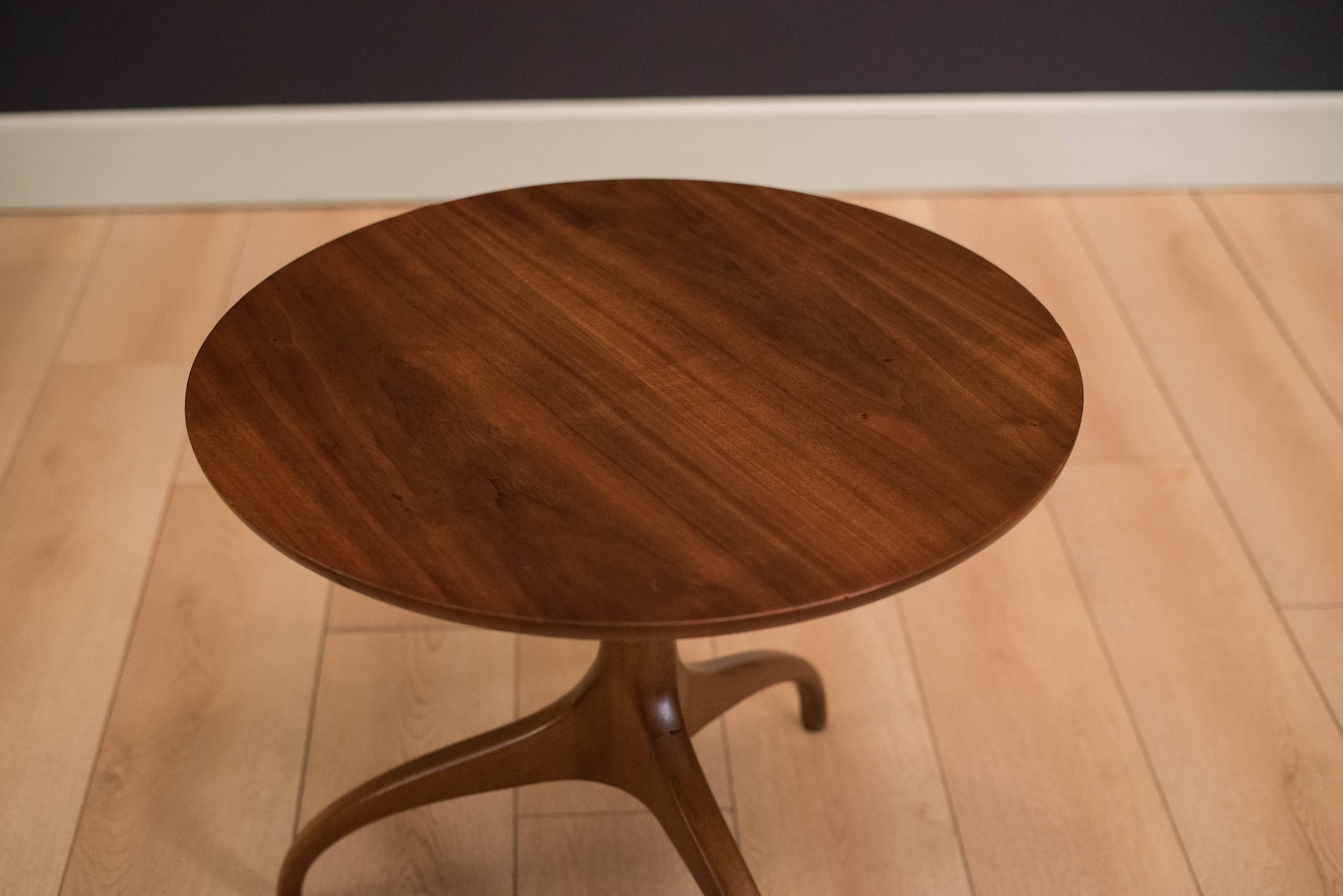 Midcentury walnut end table by Heritage-Henredon, circa 1960s. This piece features sculptural wishbone legs and a round tabletop. 

      