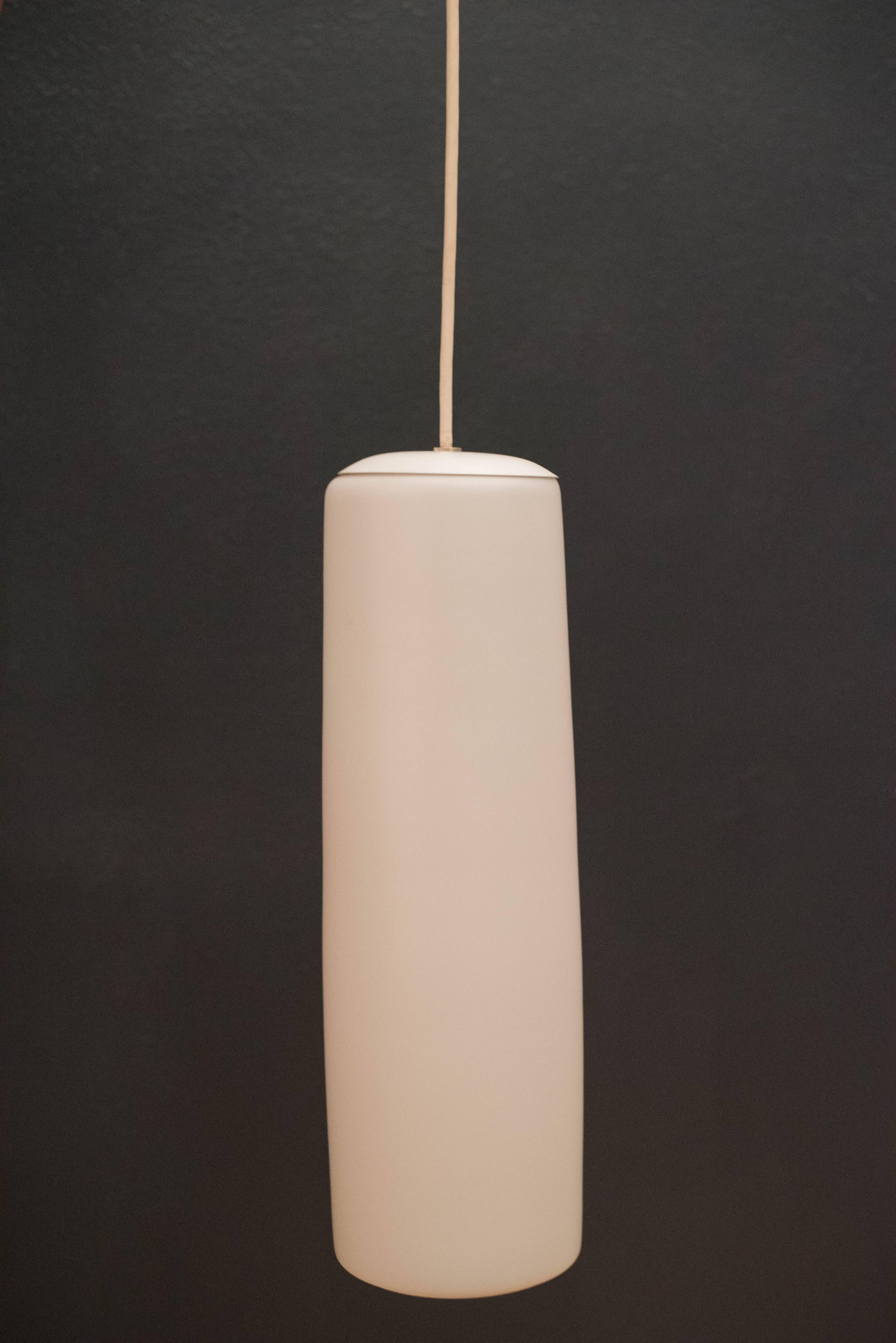 Mid-Century Modern pendant lamp manufactured by Prescolite, circa 1960s. The cylinder shade is made of frosted glass that emits a glowing light. Perfect to use for high ceilings. Price is for each, one available. 

 