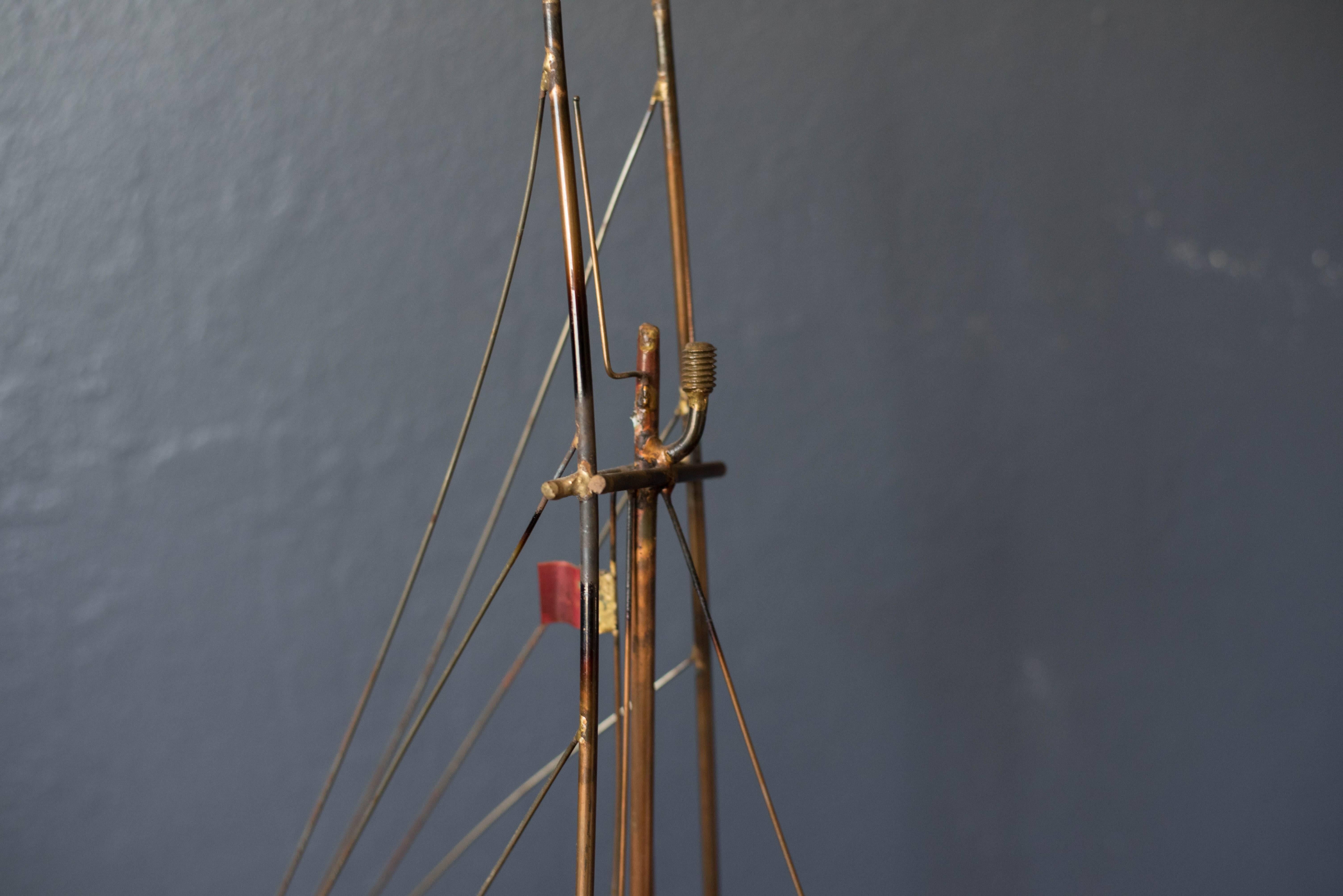 Mid-Century sailboat sculpture in brass, circa 1960s. This piece stands on a walnut base and displays vintage patina.