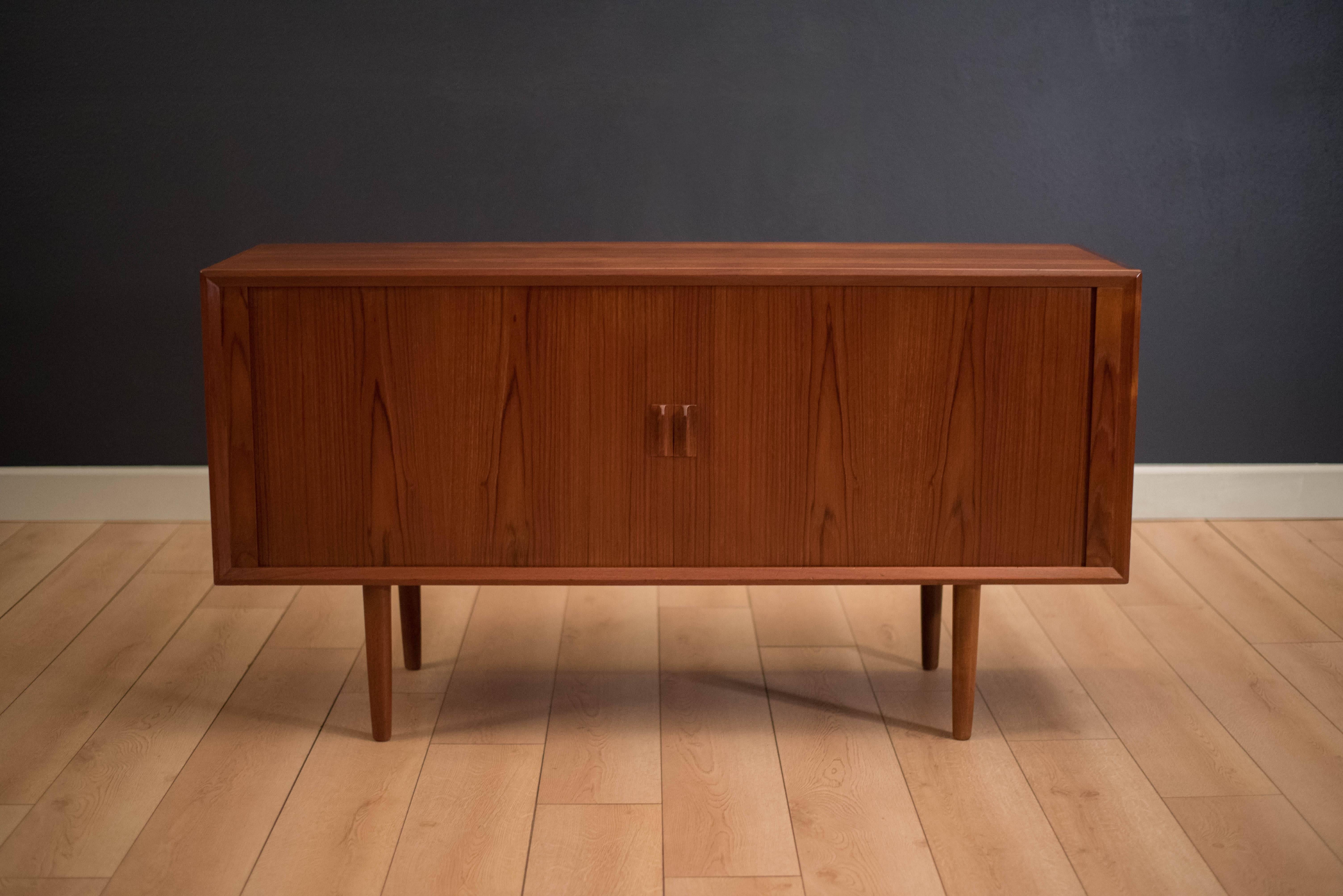 Vintage Danish credenza or entertainment console designed by Svend A. Larsen for Faarup Mobelfabrik. This piece features sliding tambour doors with sculpted teak handles. Includes one drawer, adjustable shelving, and dividers. Pull-out shelf