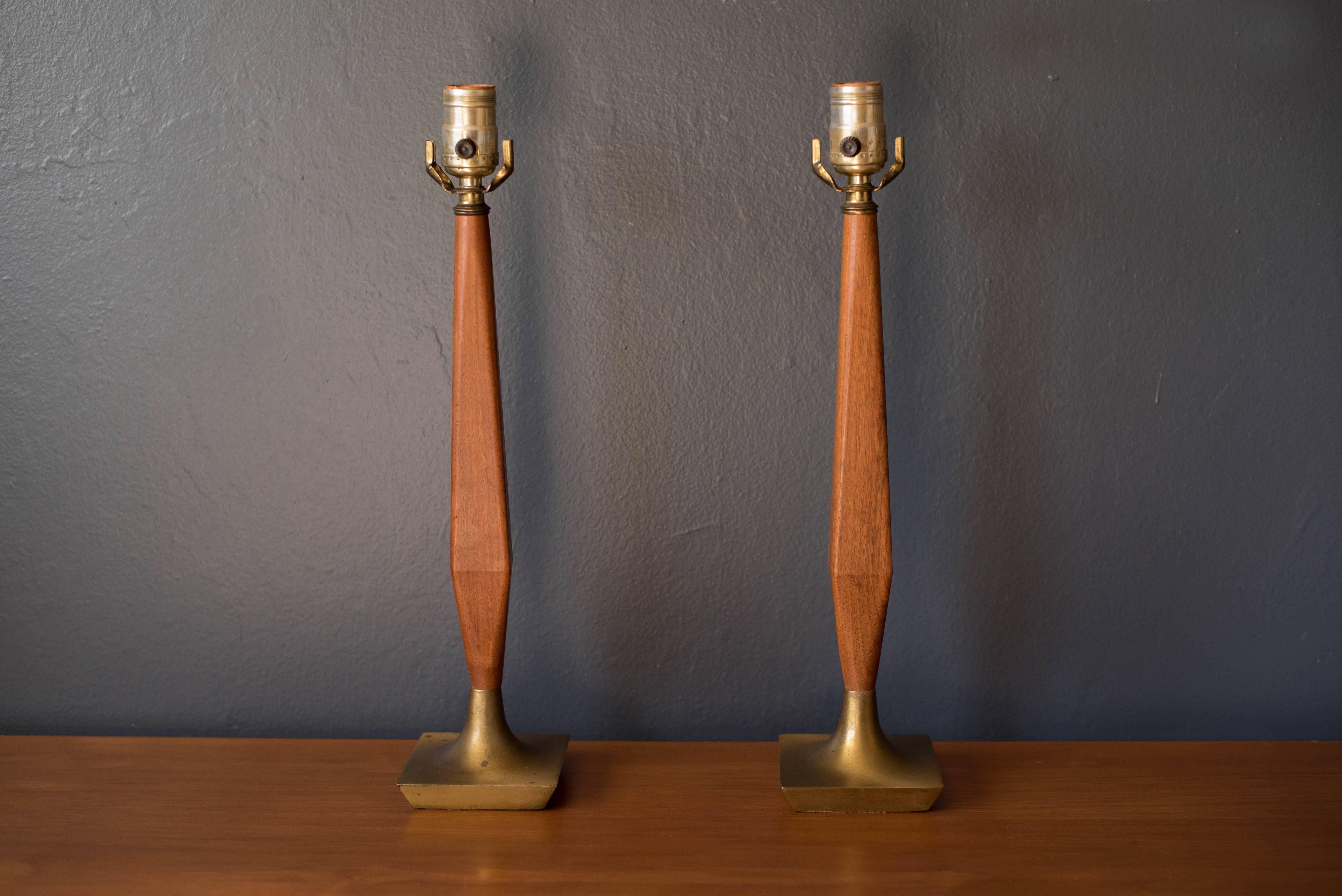 Mid-Century Modern pair of table lamps in walnut and brass. This set features sculptural walnut stems and patina on the brass bases. Includes three-way switch. Price is for the pair.