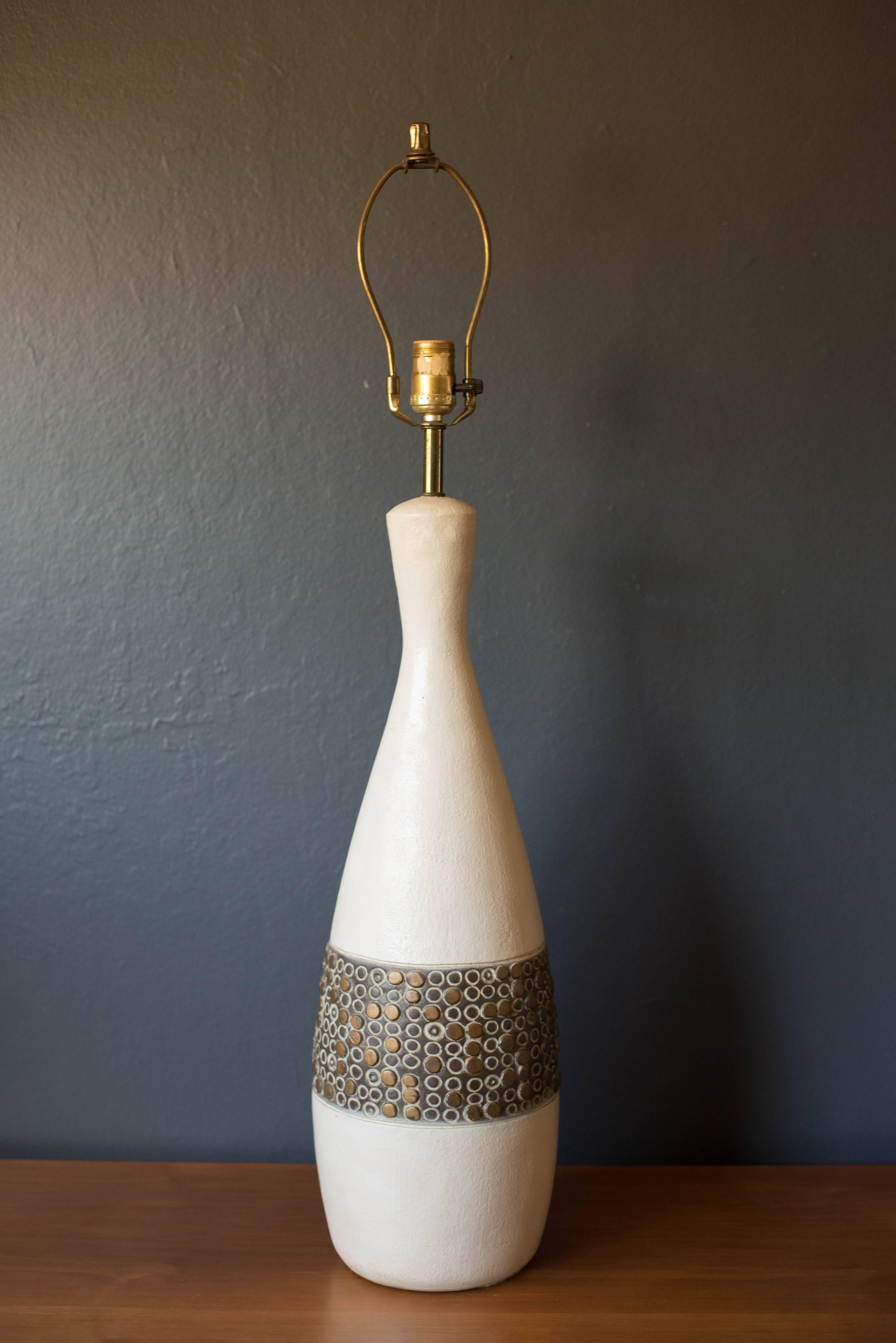 Mid-Century ceramic pottery lamp from the 1960s. This piece features a sculptural white pottery base with a raised abstract design. Includes three way switch. Marked O.W. on the back. Shade is not included.