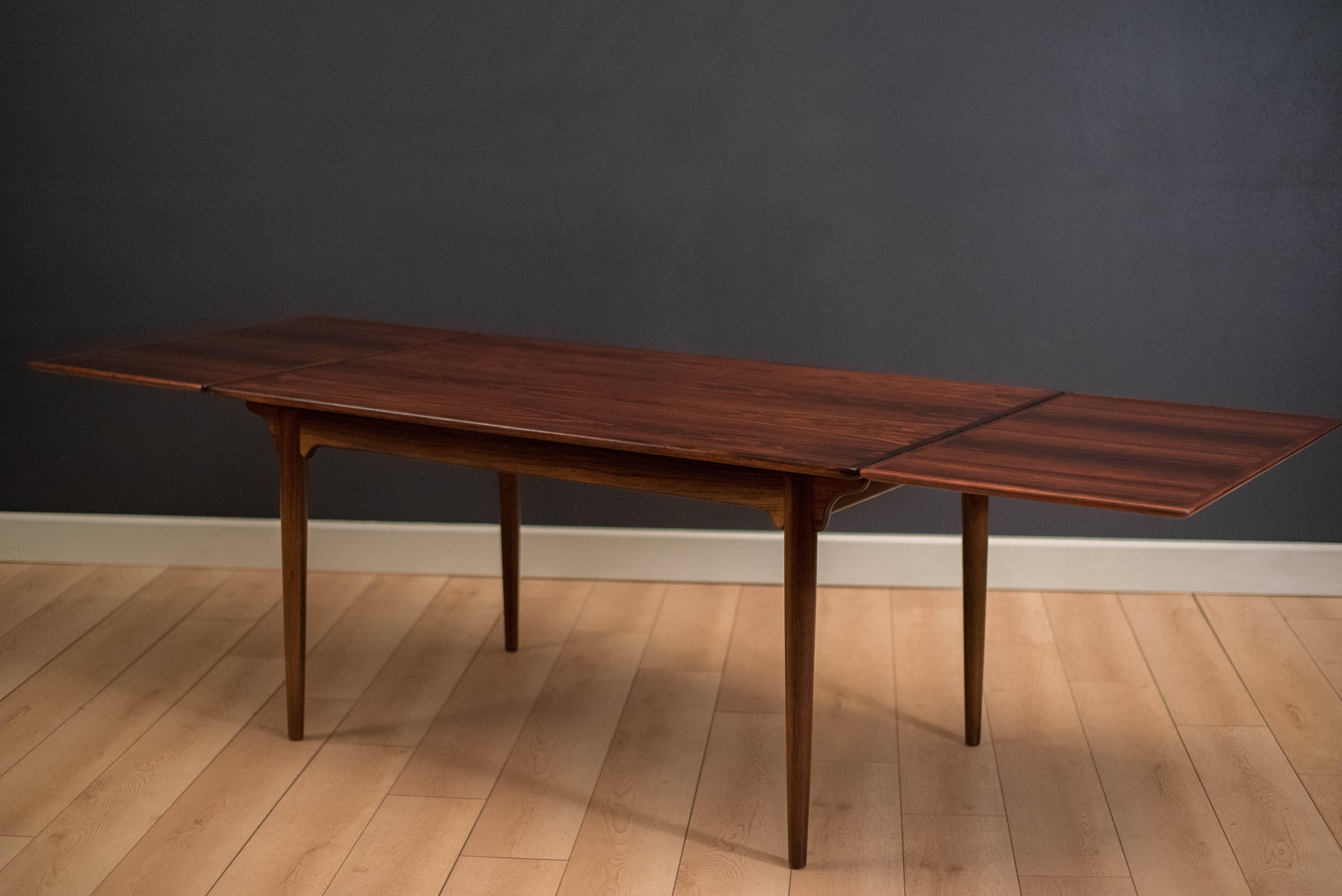 Danish modern rosewood dining table designed by Gunni Omann for Omann Jun Mobelfabrik. This piece features stunning rosewood grains and a unique sculpted base. Table expands with two leaves that tuck underneath when not in use. 

Table measures