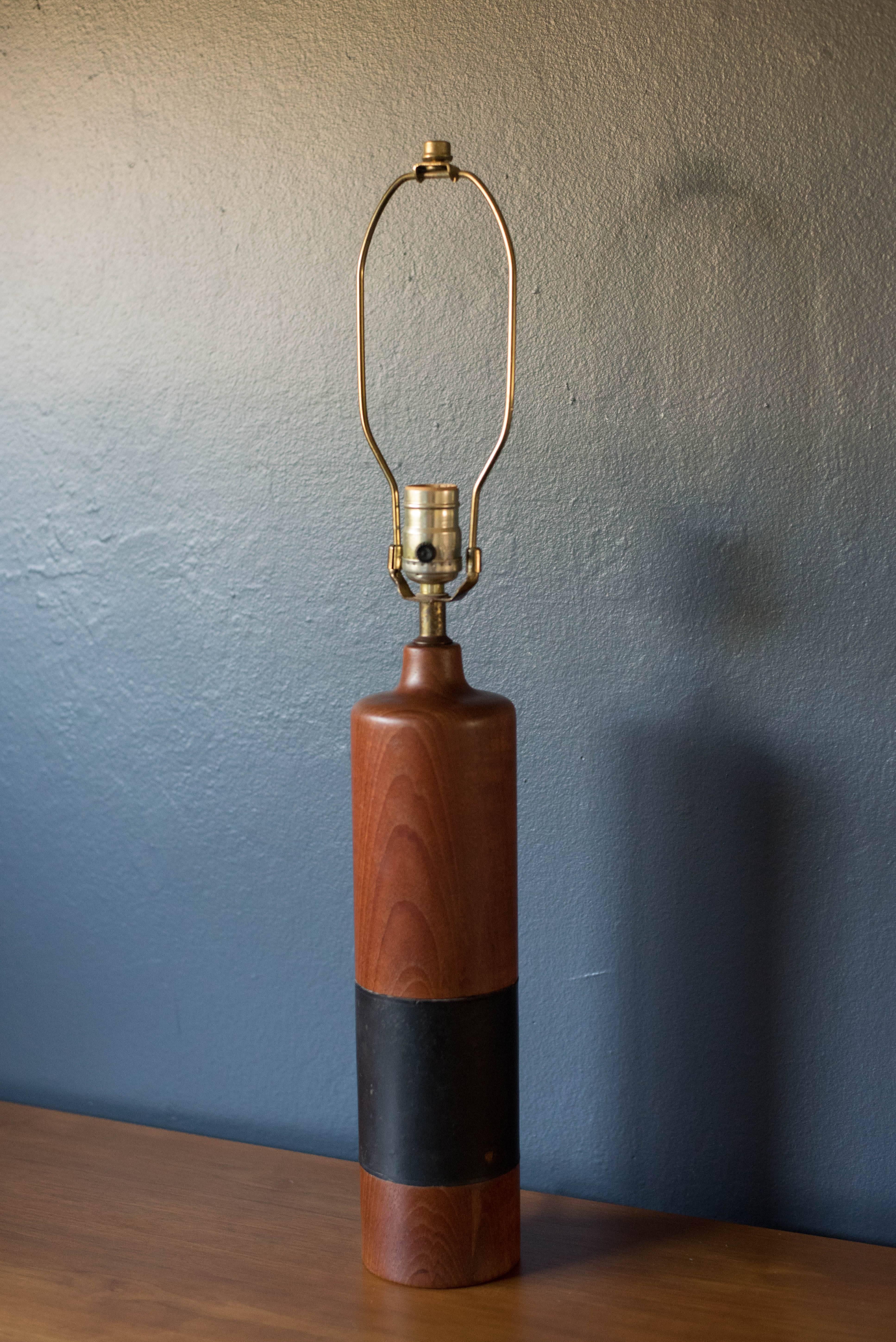 Mid-Century teak lamp made in Denmark, circa 1960s. The piece features a black leather band and includes a three way switch. 

         