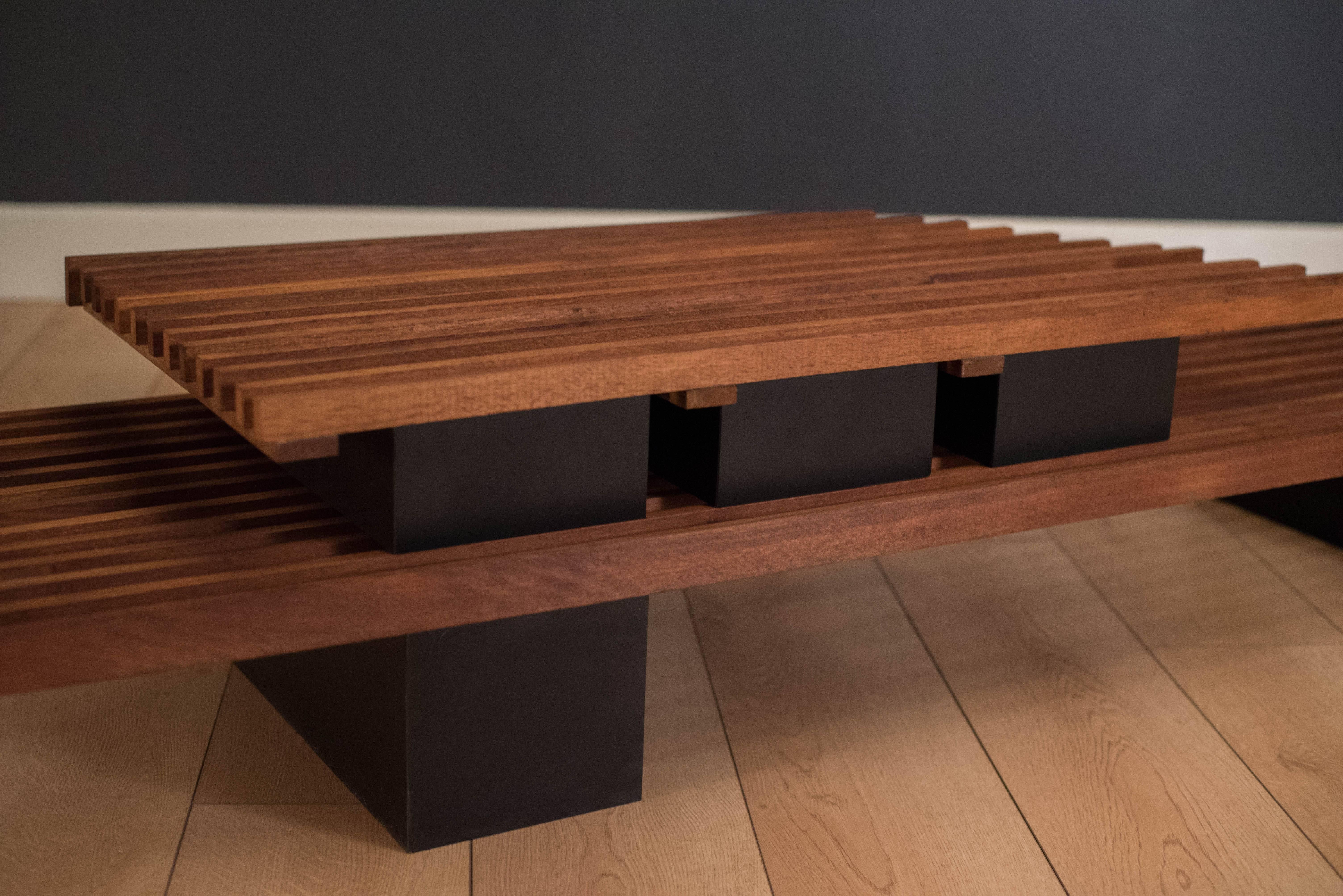 American Studio Craft slat bench coffee table in walnut. This unique piece has a low black laminate platform base. Top is modular and can be configured in any arrangement. 

Measures: Lower base 9