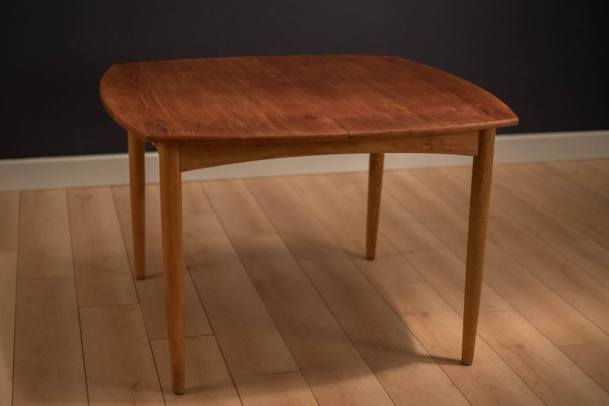 Mid-Century Modern dining table designed by William Watting for Brande Møbelfabrik, Denmark. This piece has a teak tabletop with oak edge banding and base. Includes butterfly leaf extensions that cleverly store under the table. 

Table extends to