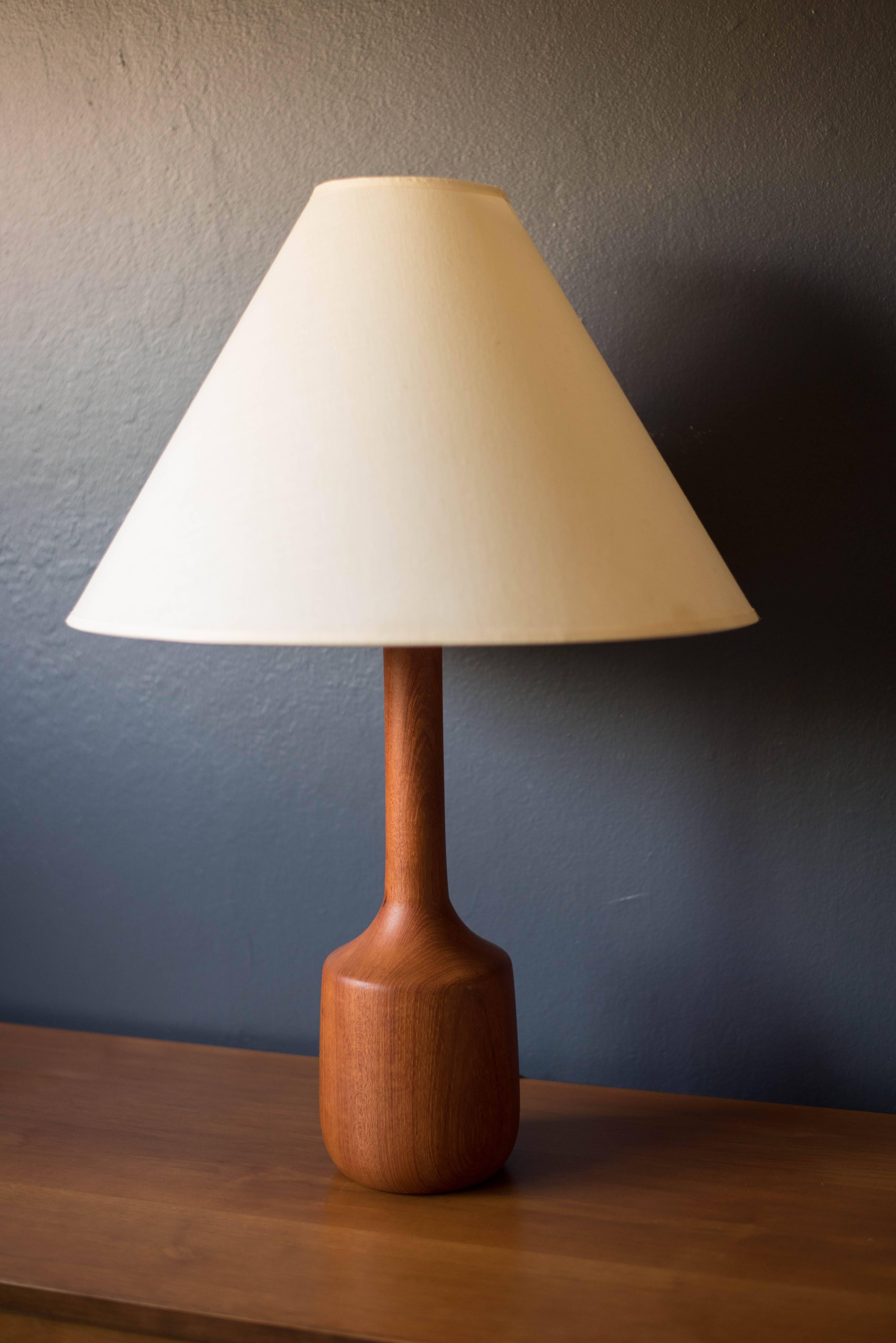 Mid-Century Table lamp with solid teak base. This piece includes a three way switch and triangular linen shade.
   
