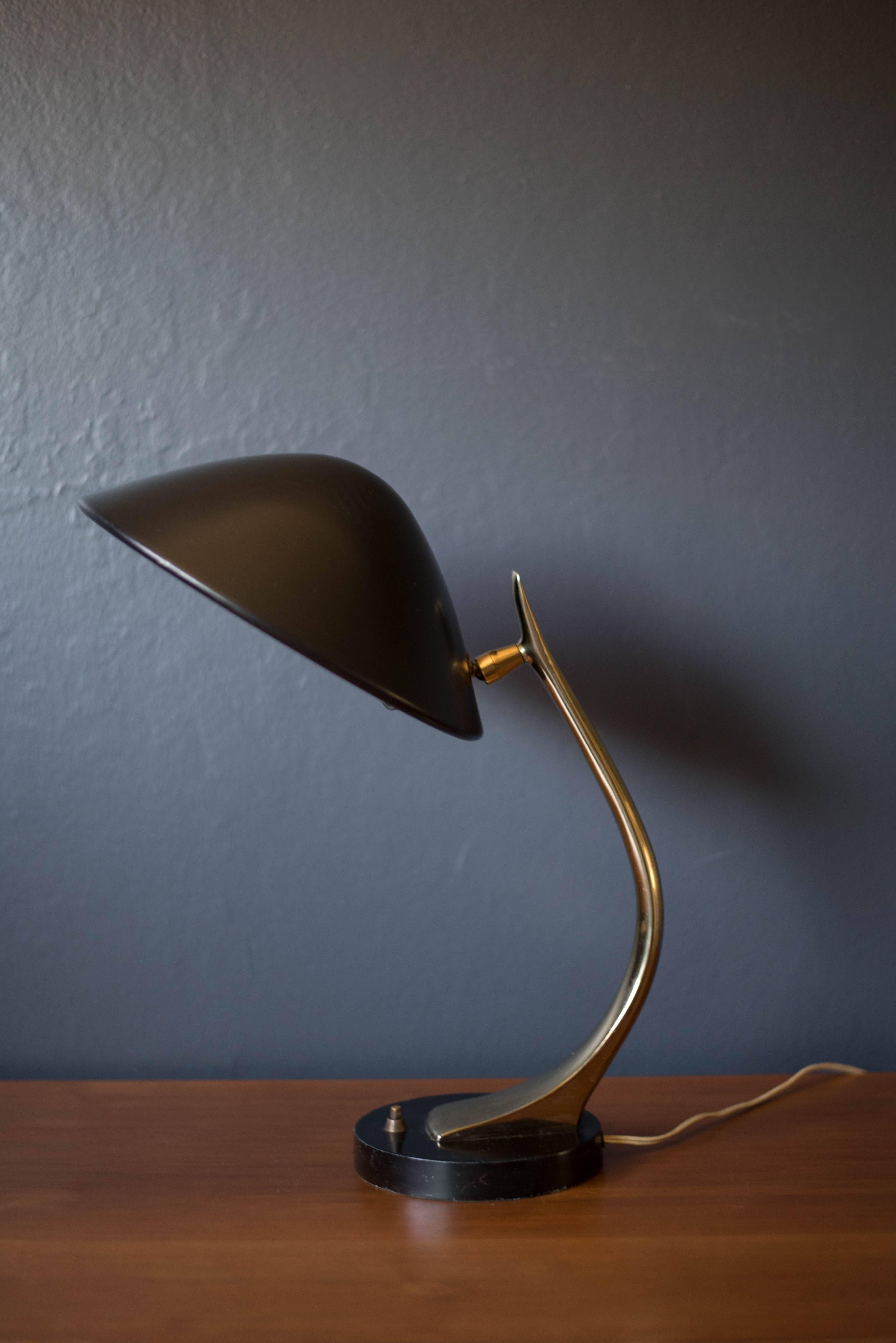 Mid Century adjustable desk or table lamp by Laurel Lamp Co., circa 1970s. This piece is brass-plated with a black lacquered shade and base. Features an adjustable neck and tilting head.