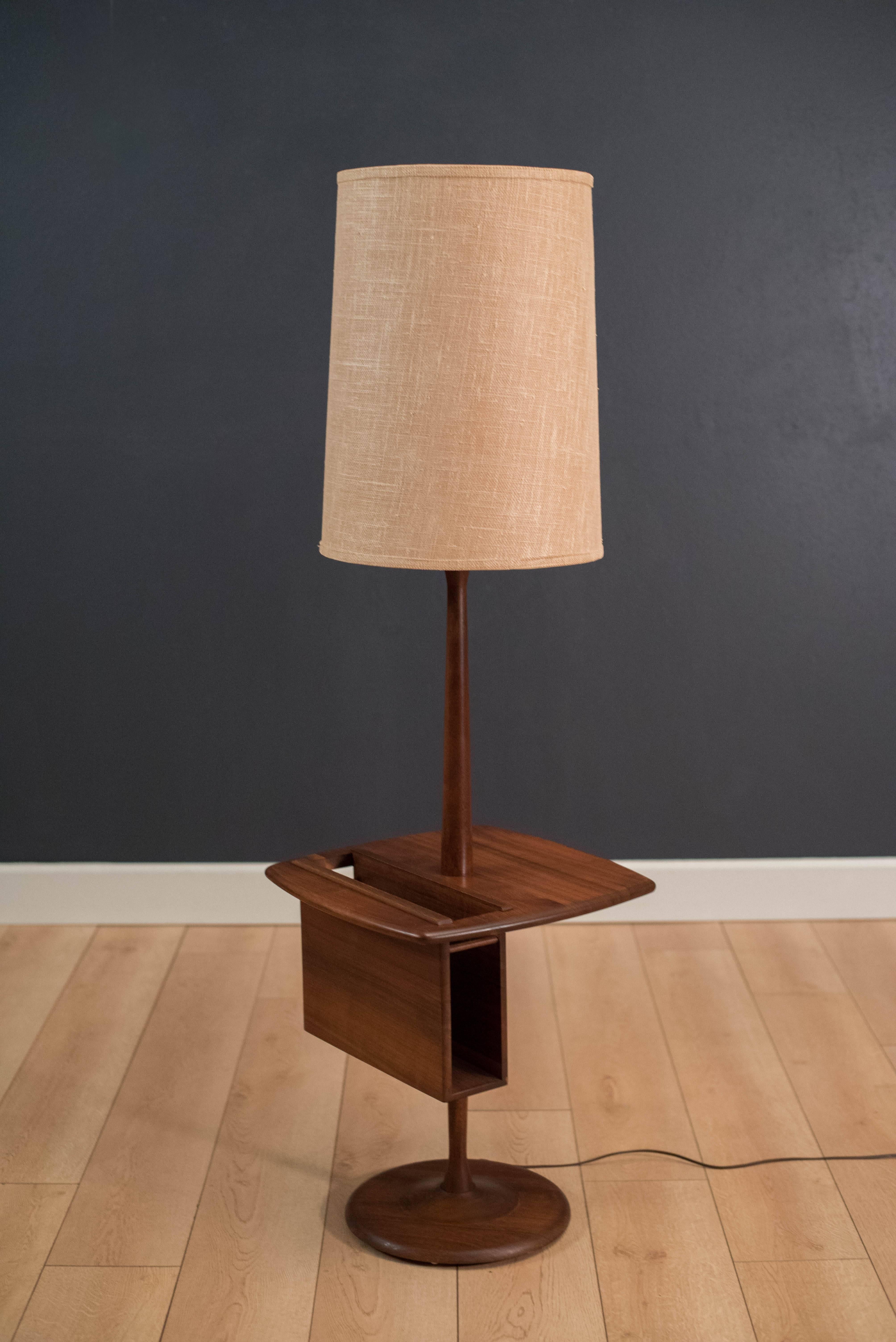 Vintage Laurel floor lamp in walnut with attached side table. This functional piece includes a magazine holder built in to the side table. Lamp has a three way switch mechanism and includes the shade. 

